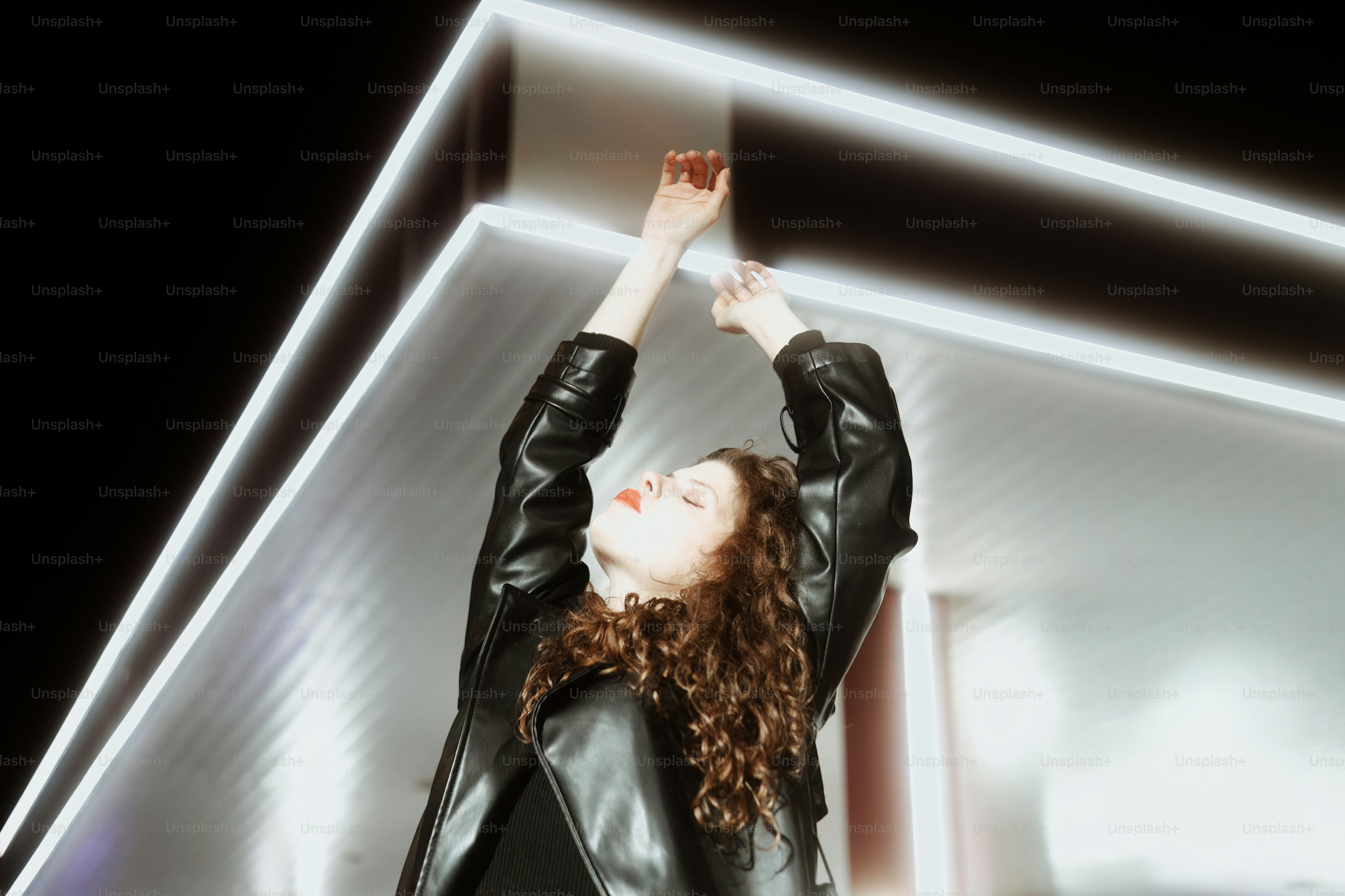 A woman in a black leather jacket standing in front of a building photo ...