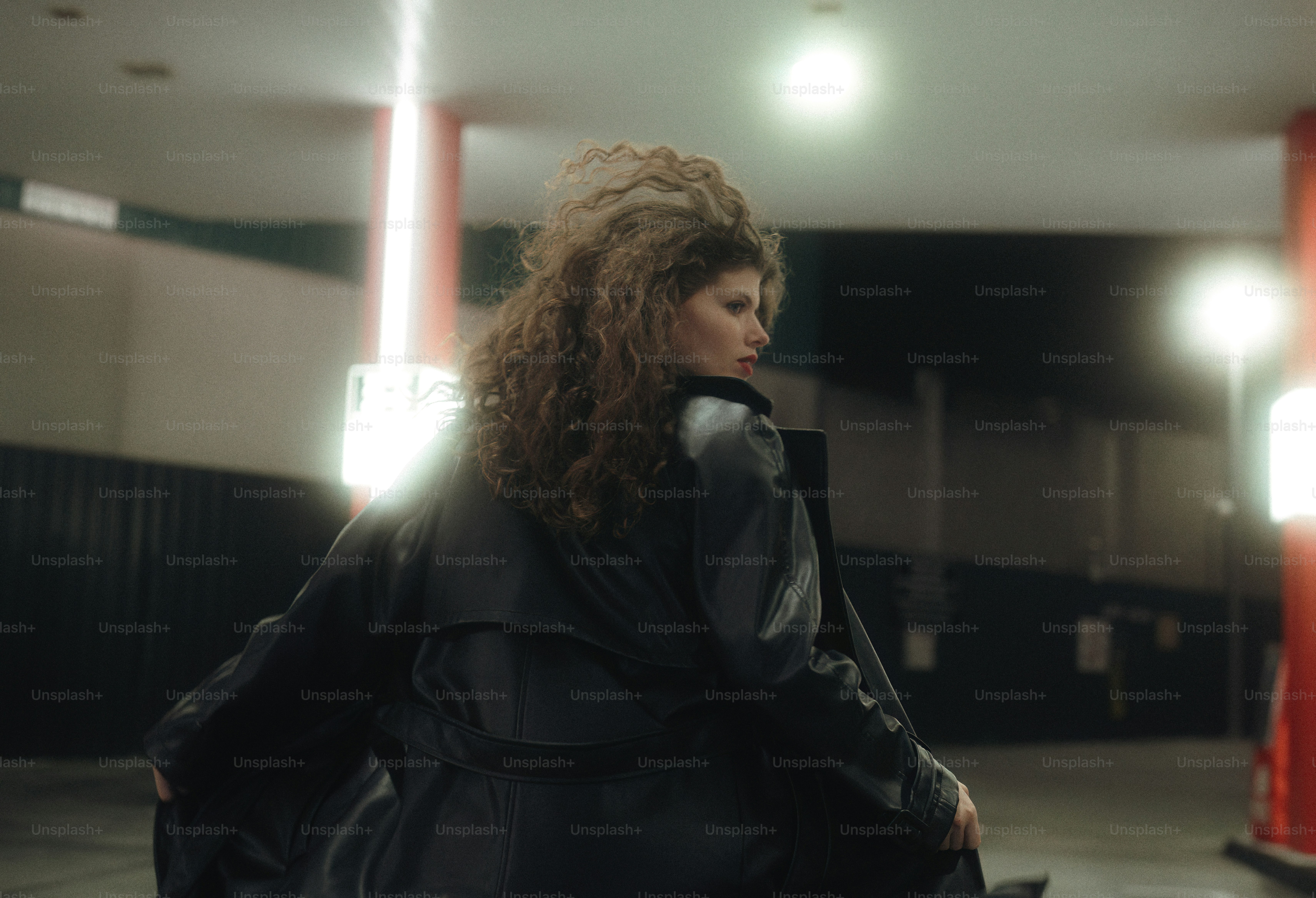 A woman in a black leather jacket standing in front of a fence photo ...
