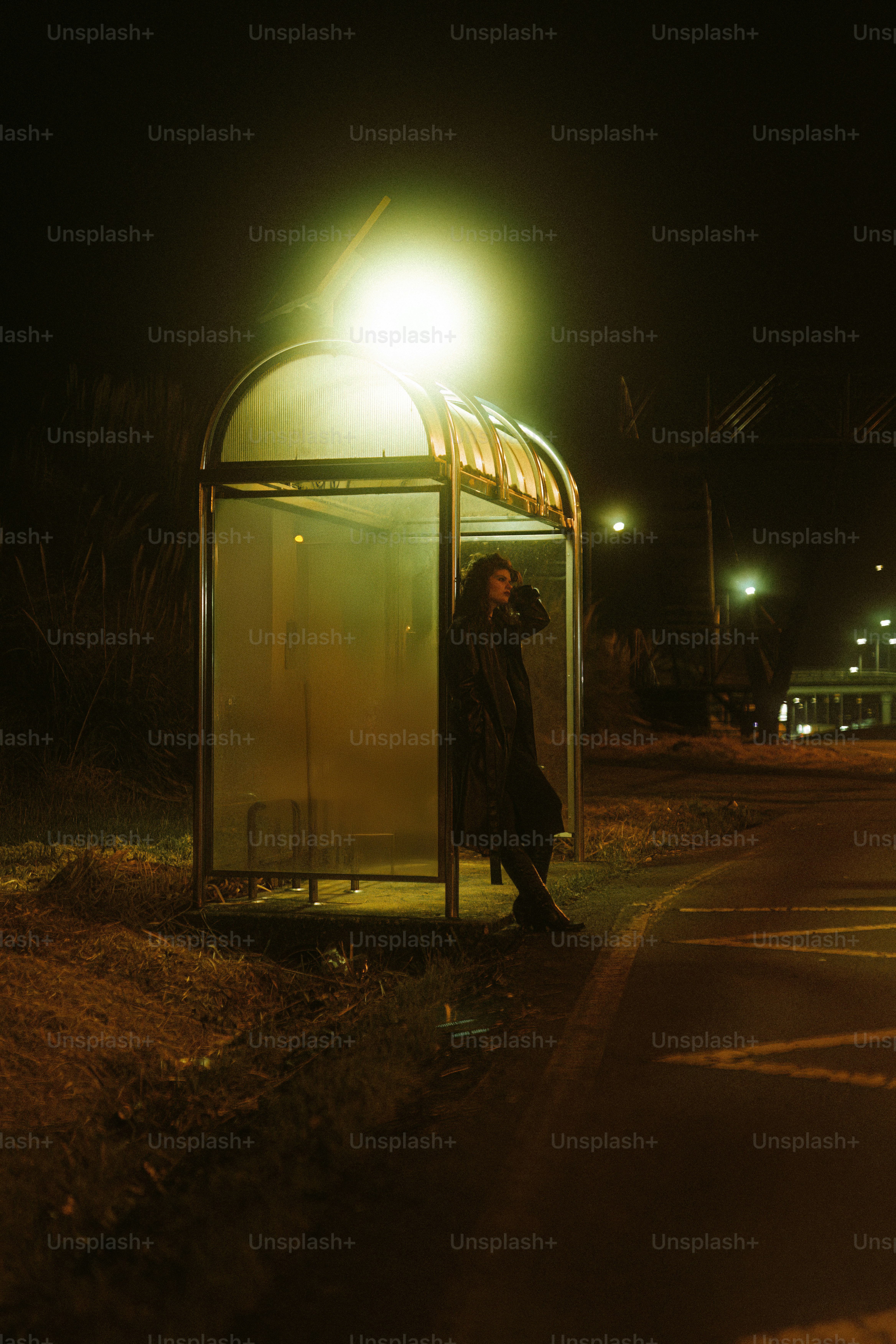 A man standing next to a bus stop at night