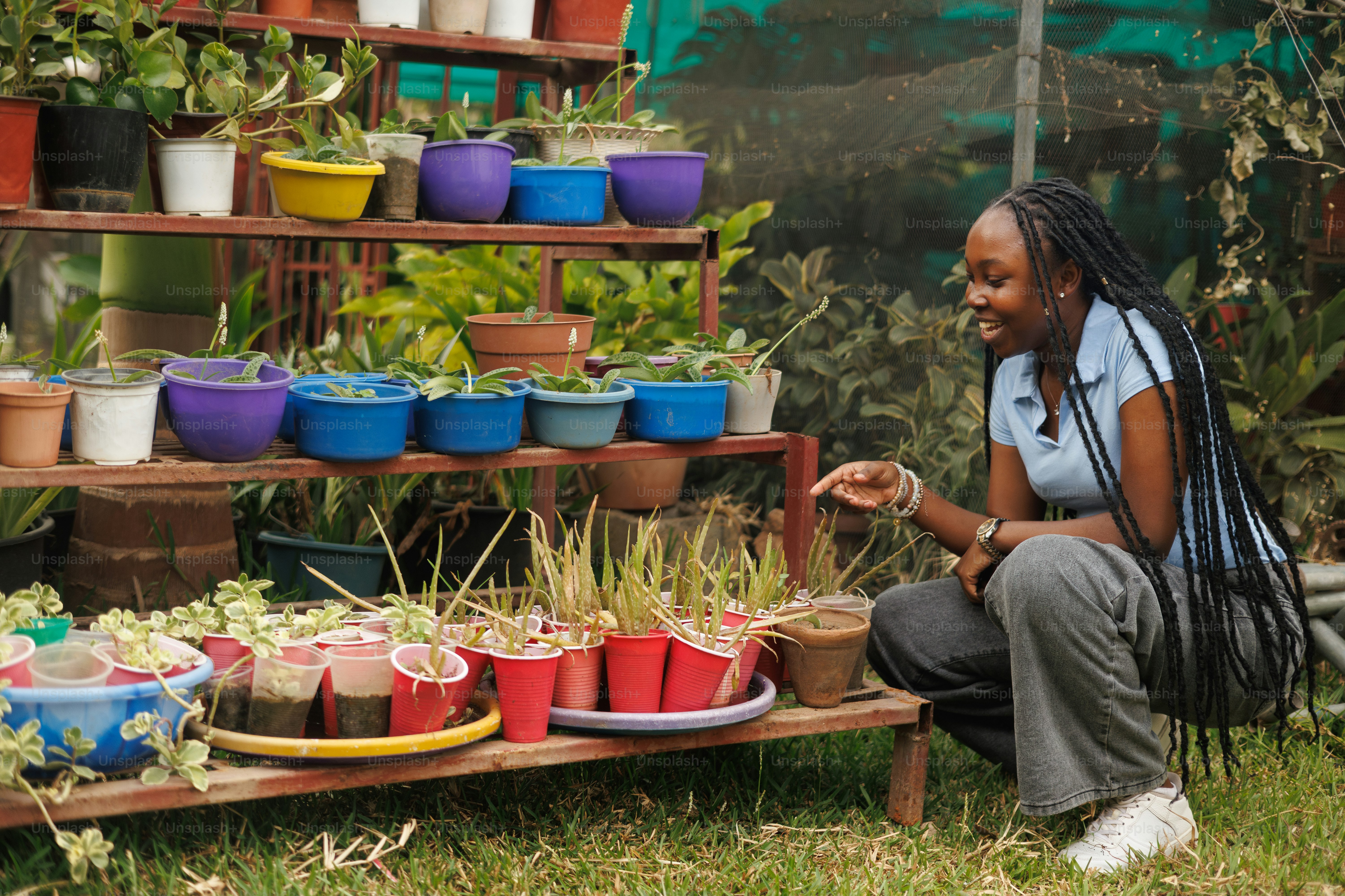 A woman sitting in front of a shelf of potted plants