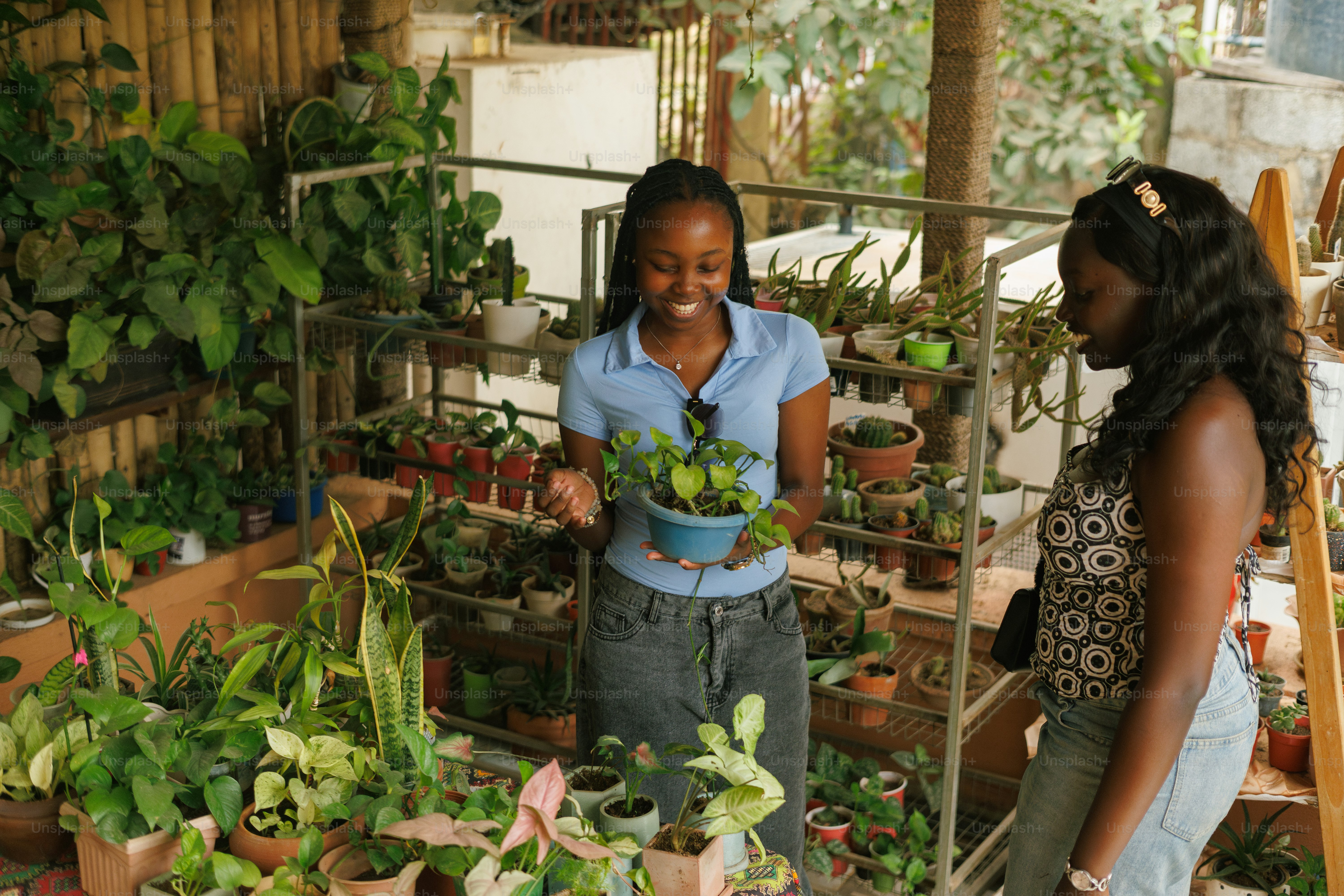 Um par de mulheres de pé uma ao lado da outra em uma sala cheia de plantas