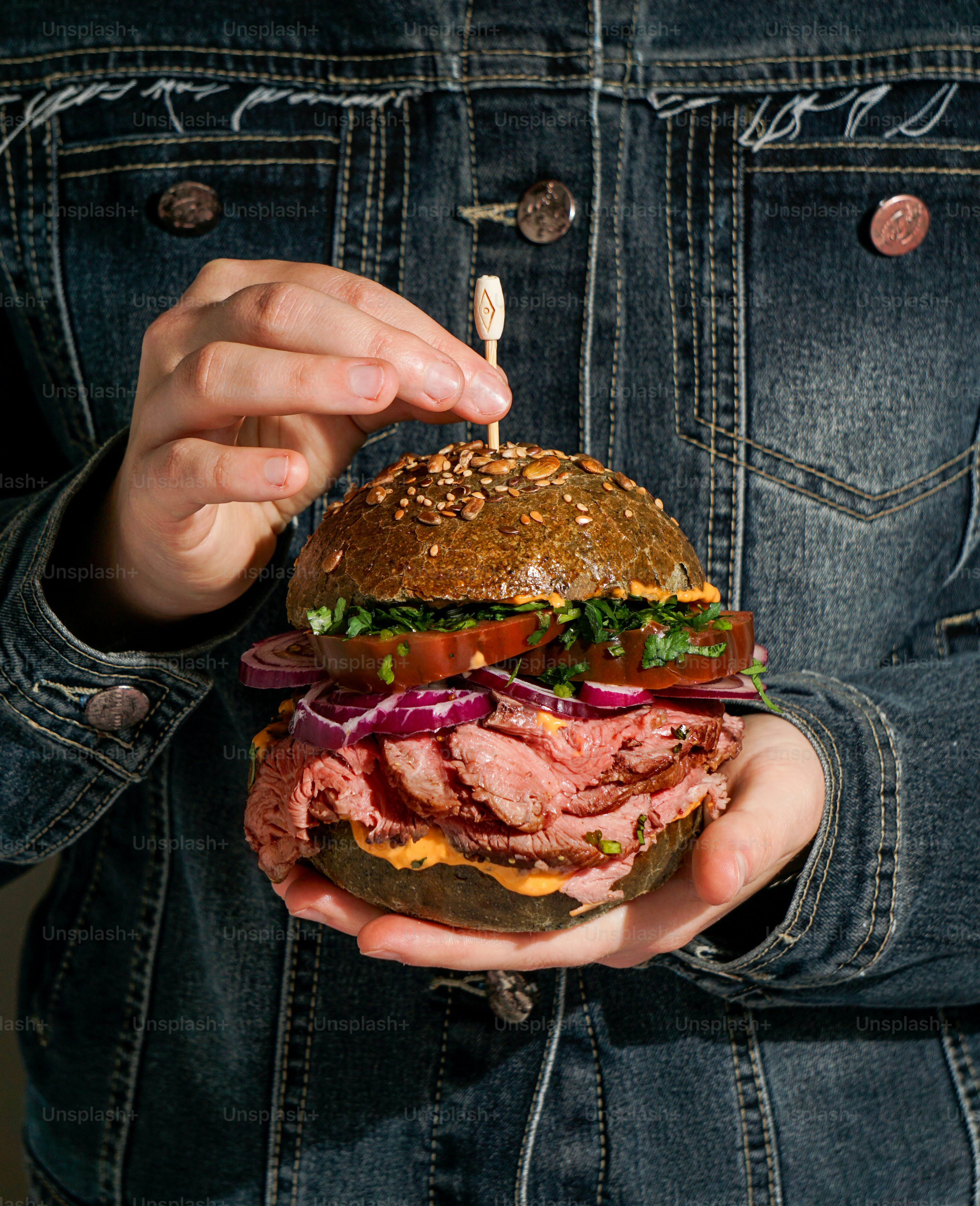 A person holding a large sandwich in their hands