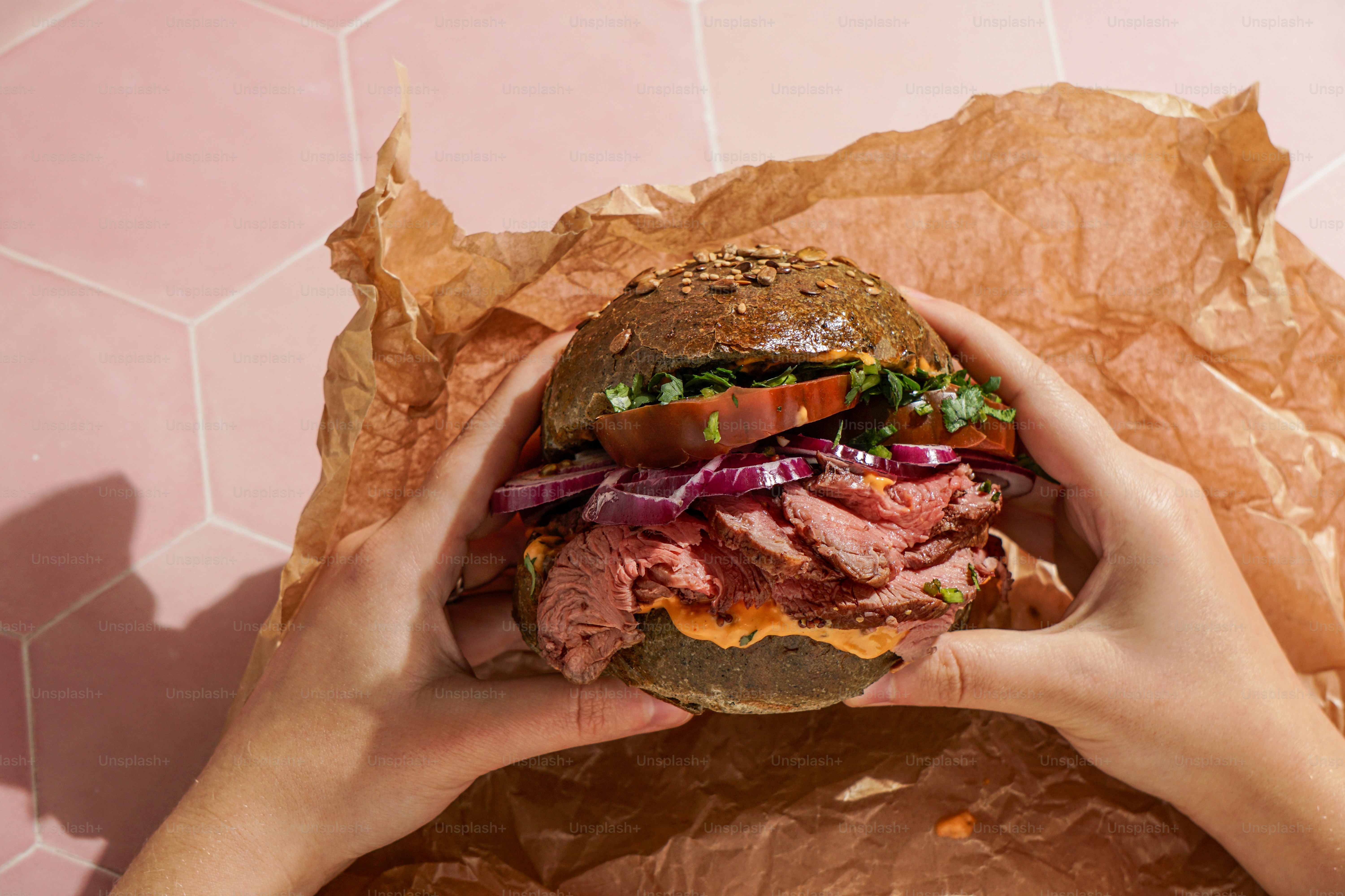 A person holding a large sandwich in their hands