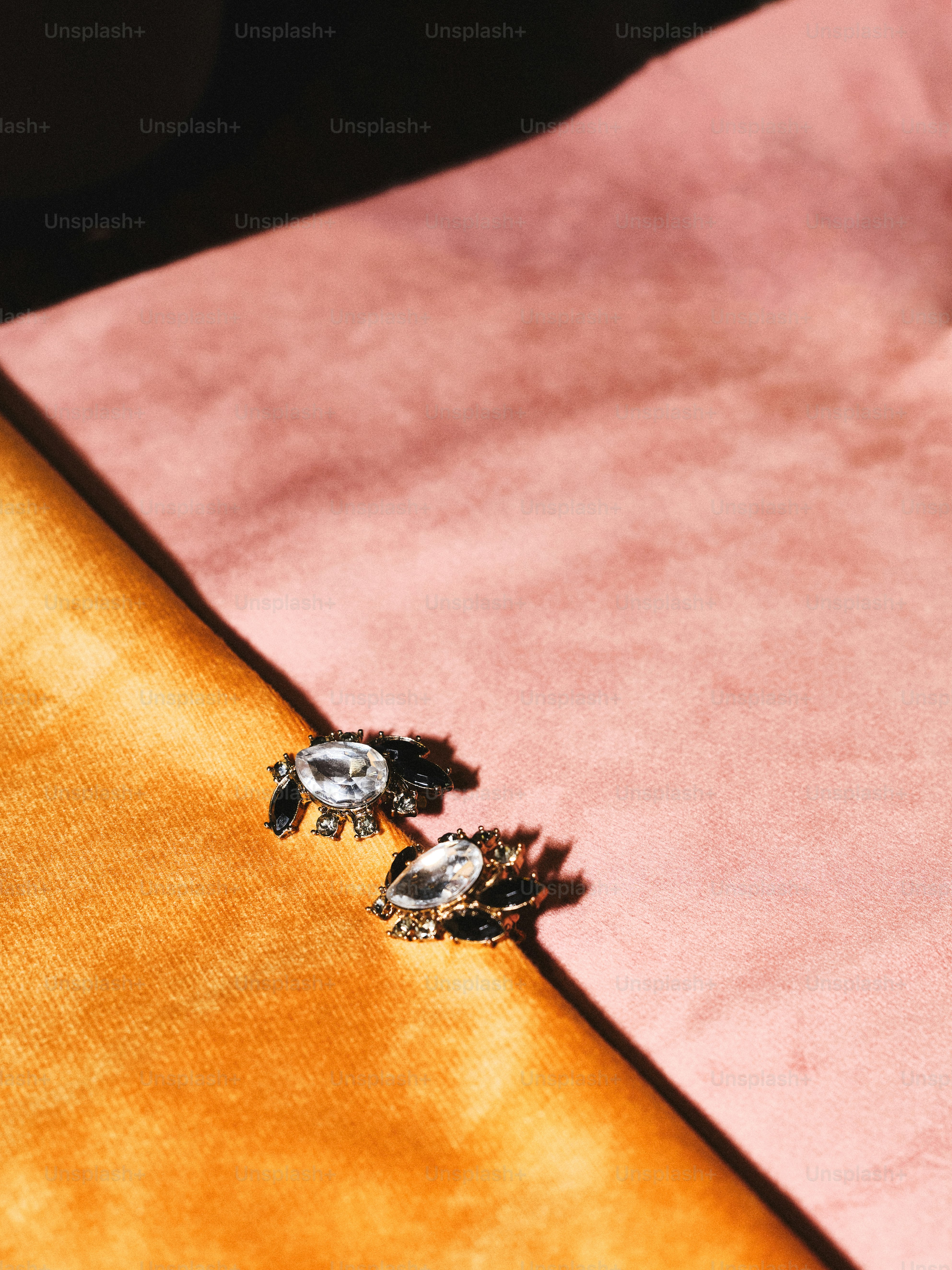 A pair of earrings sitting on top of a pink blanket