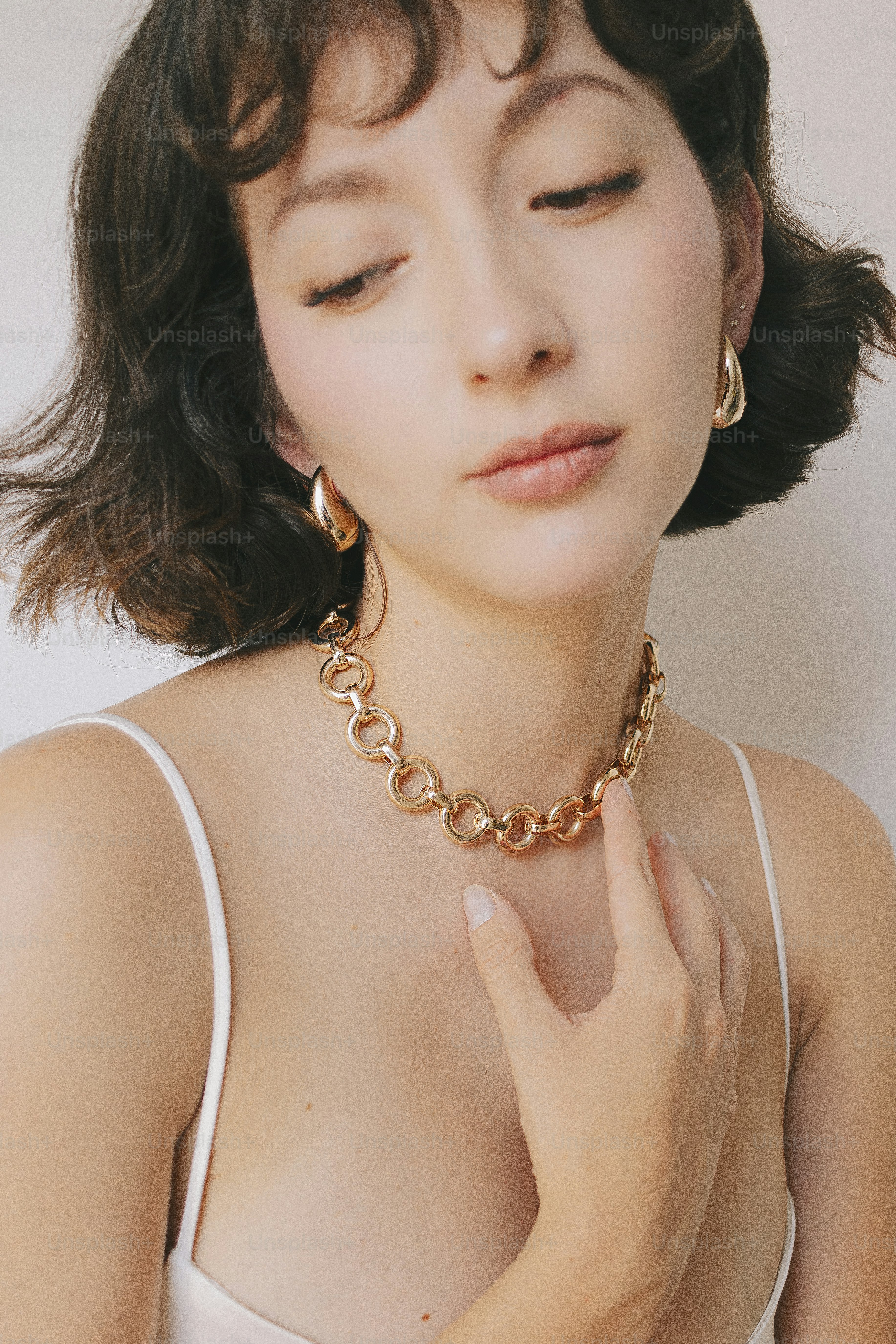 A woman in a white tank top wearing a gold necklace