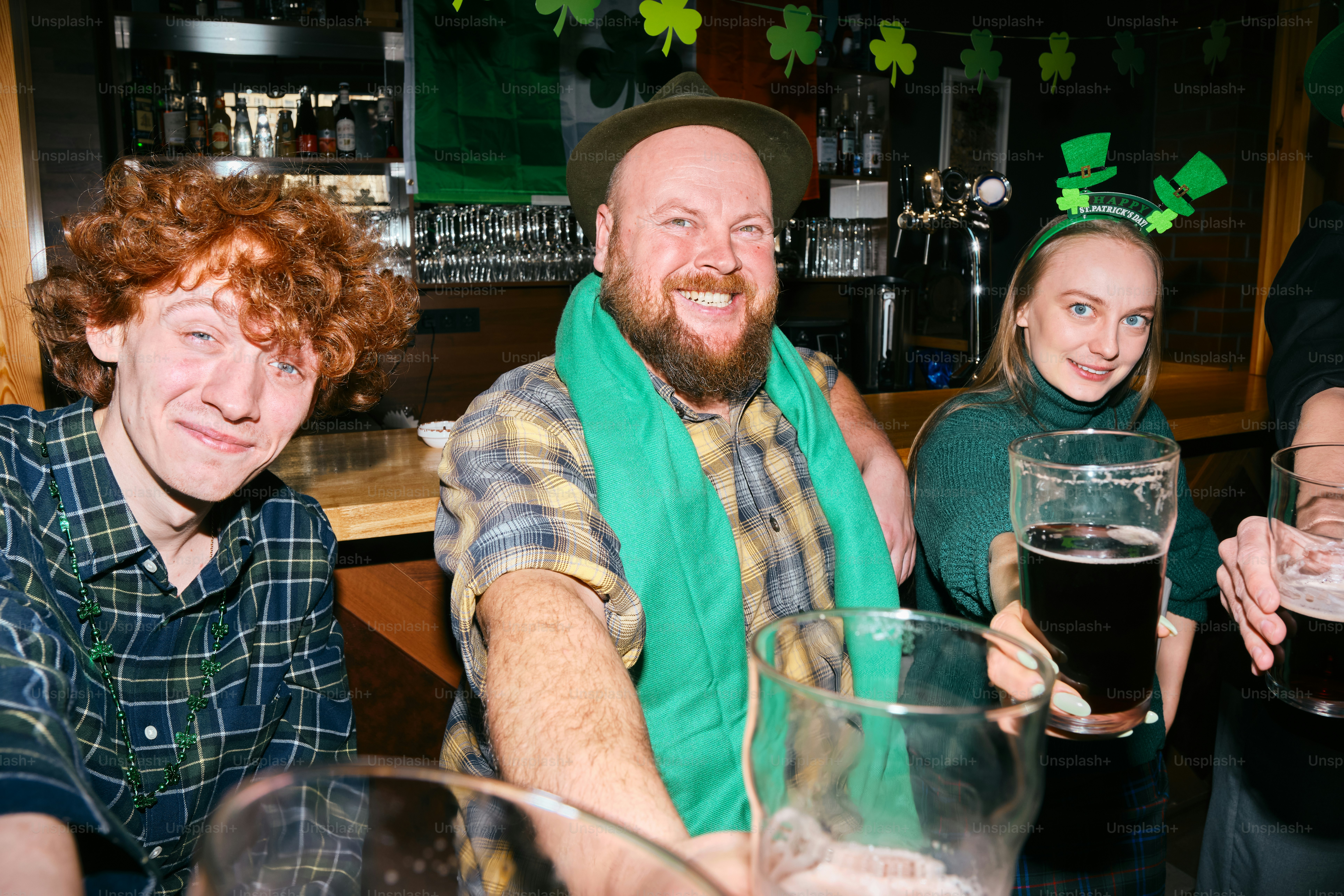 A group of people sitting at a bar with glasses of beer