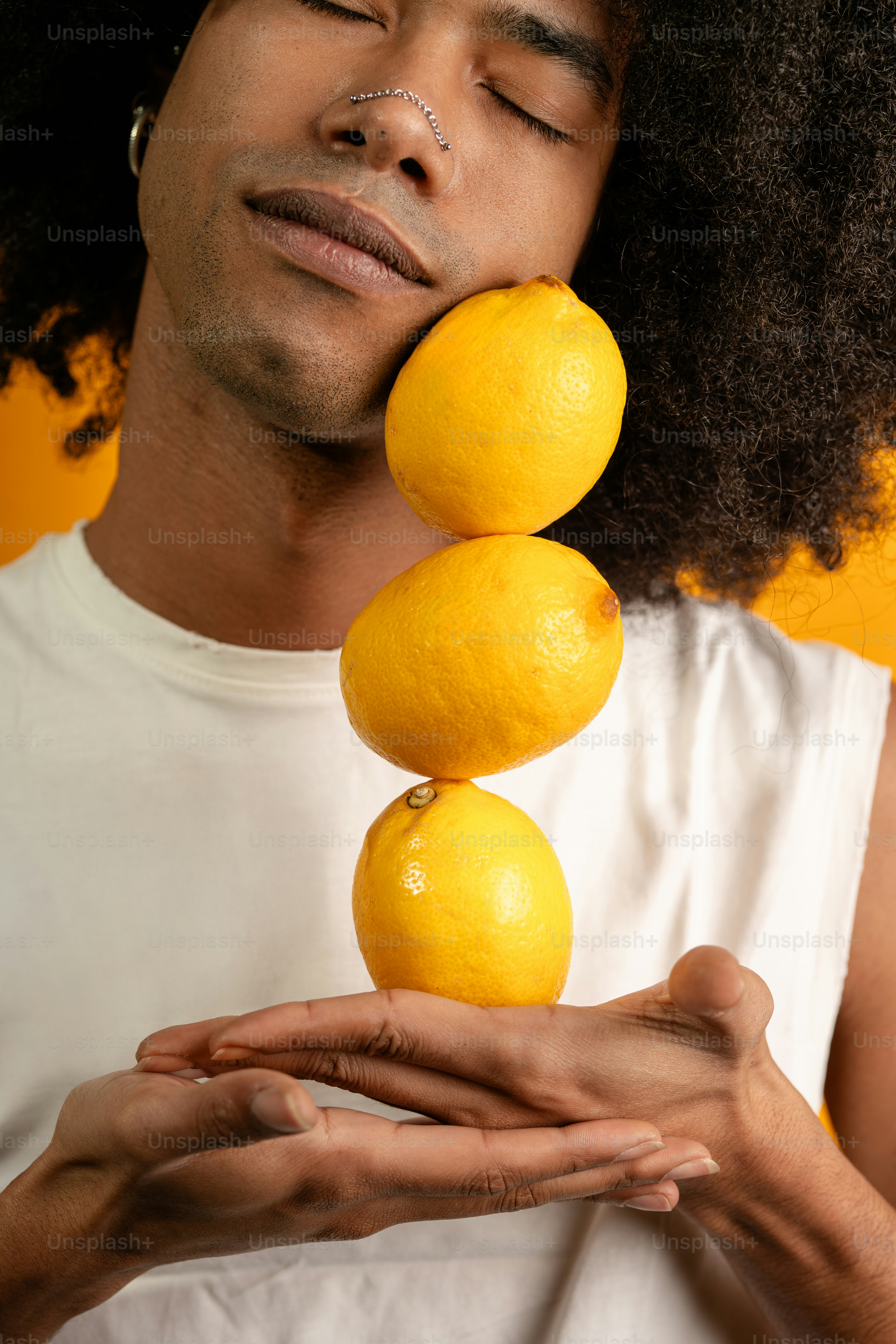 Ein Mann hält drei Zitronen vor sein Gesicht