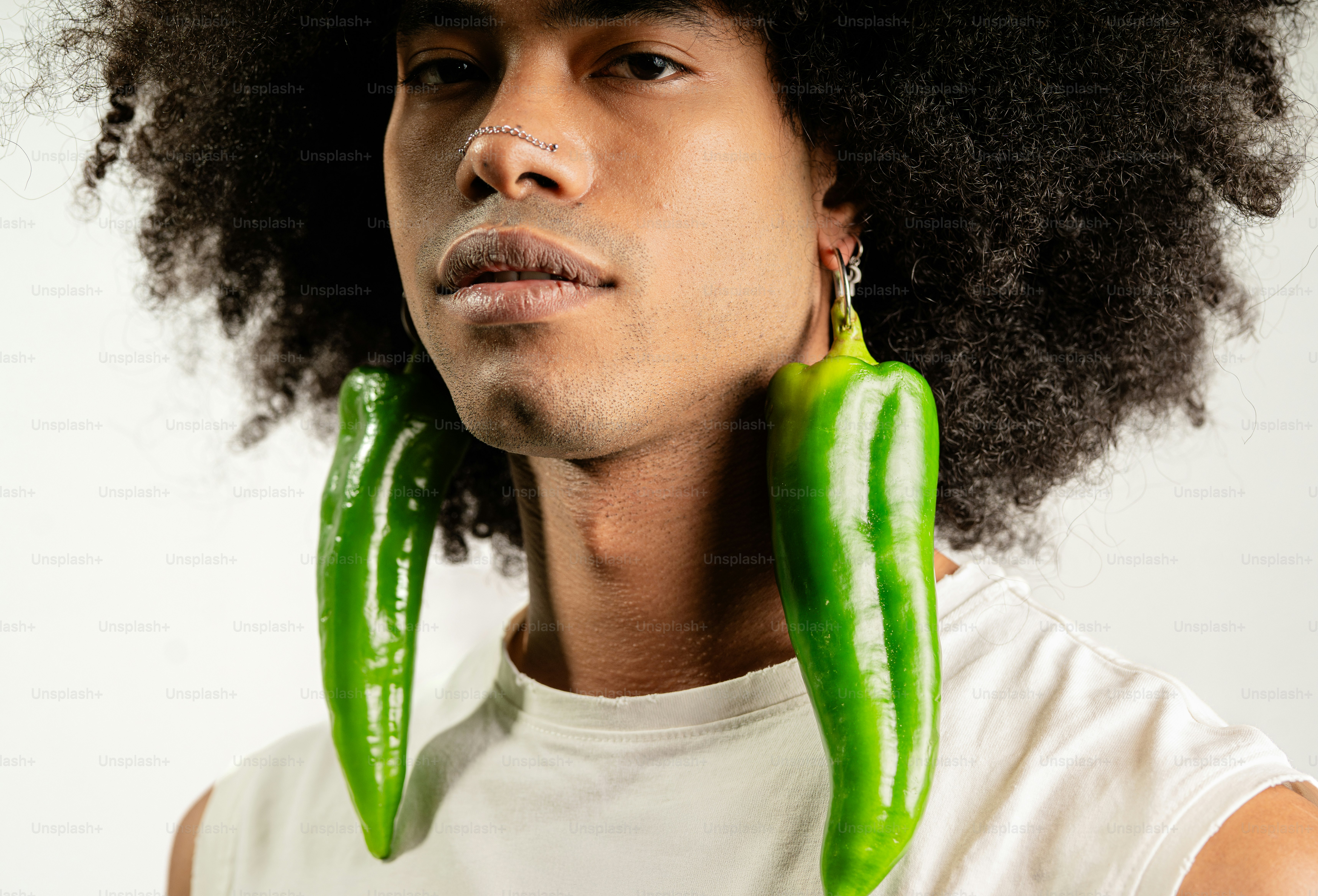 A man with a pair of green peppers in his ear