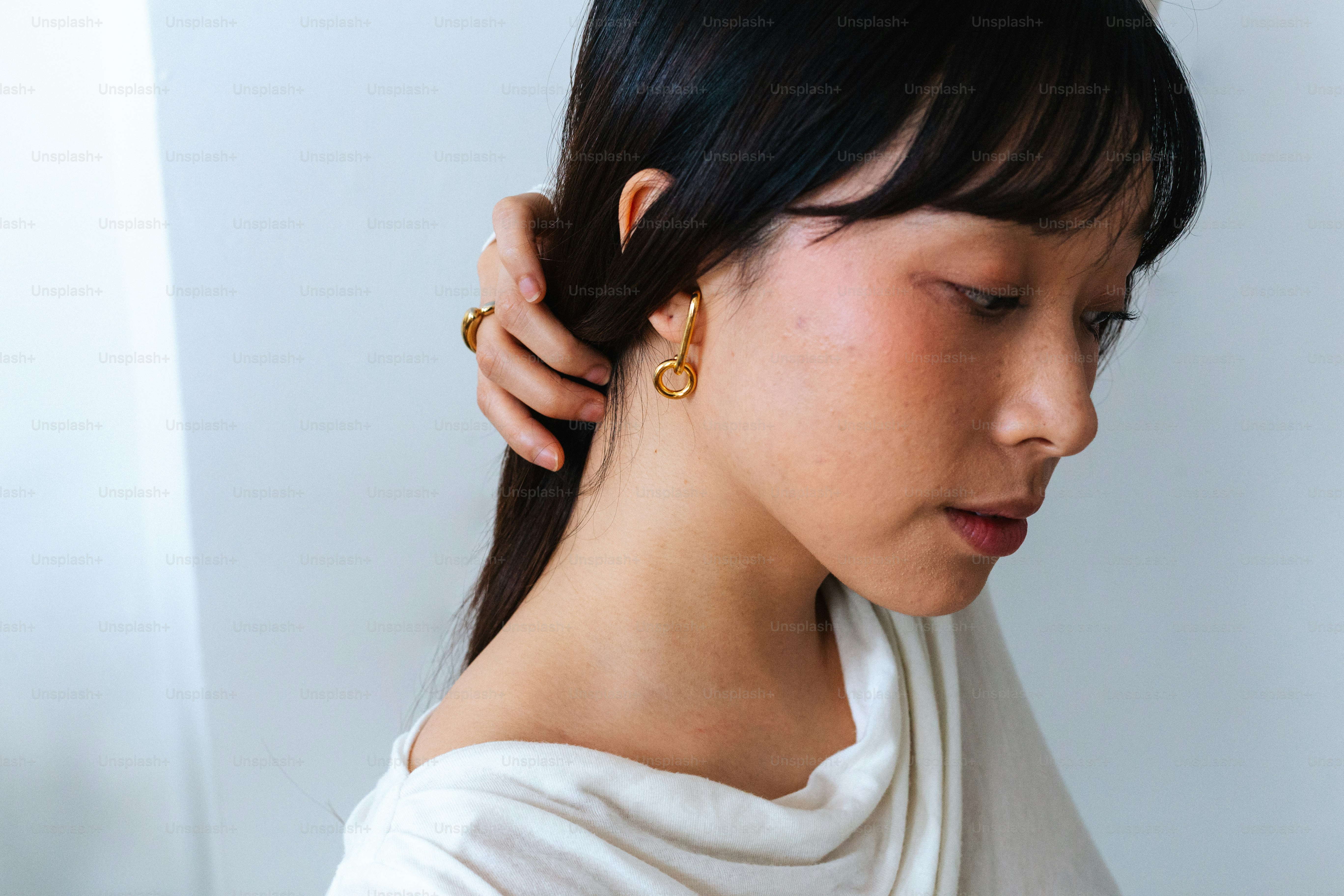 A woman wearing a white shirt and gold earrings