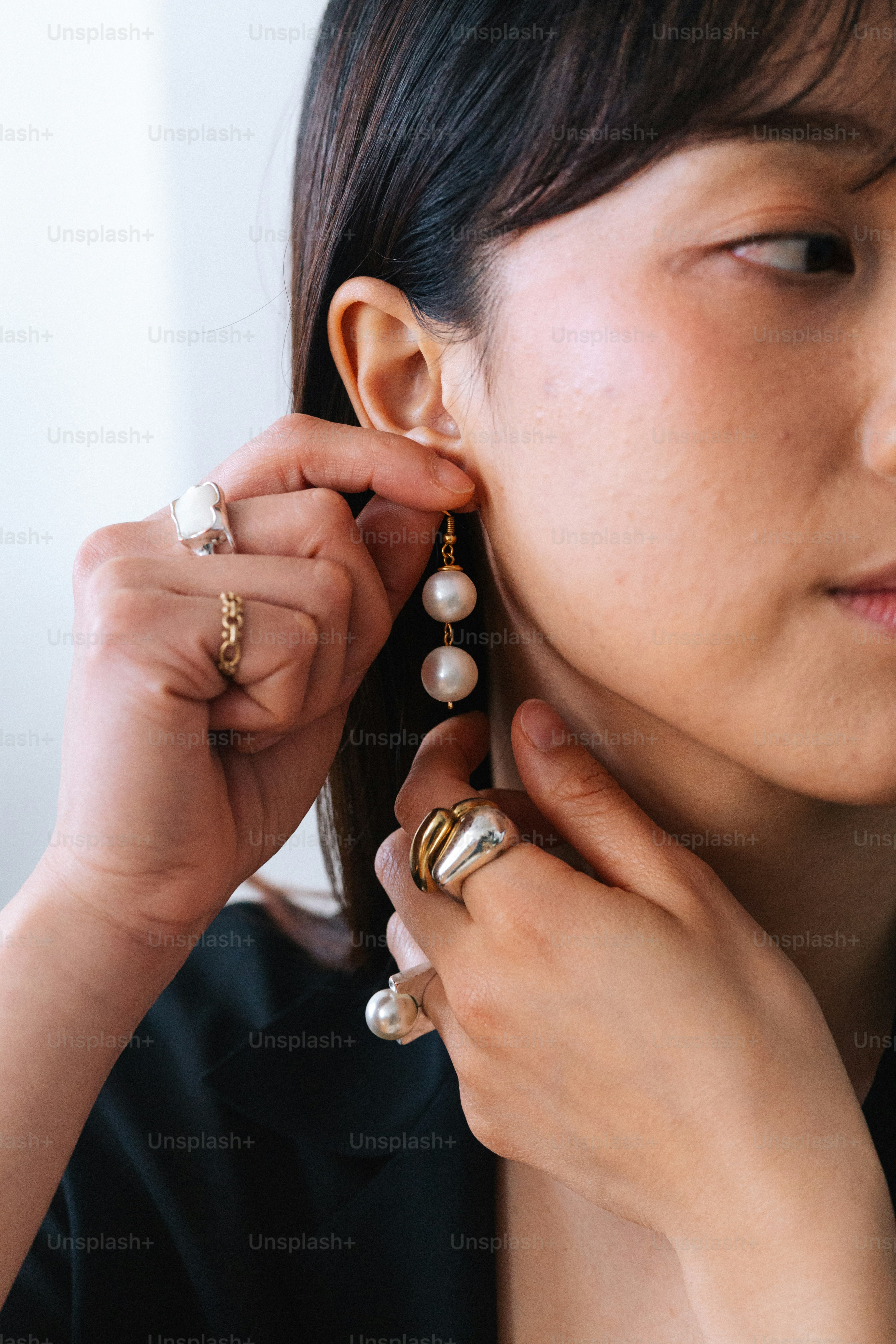 Eine Frau, die ein Paar Perlenohrringe anlegt