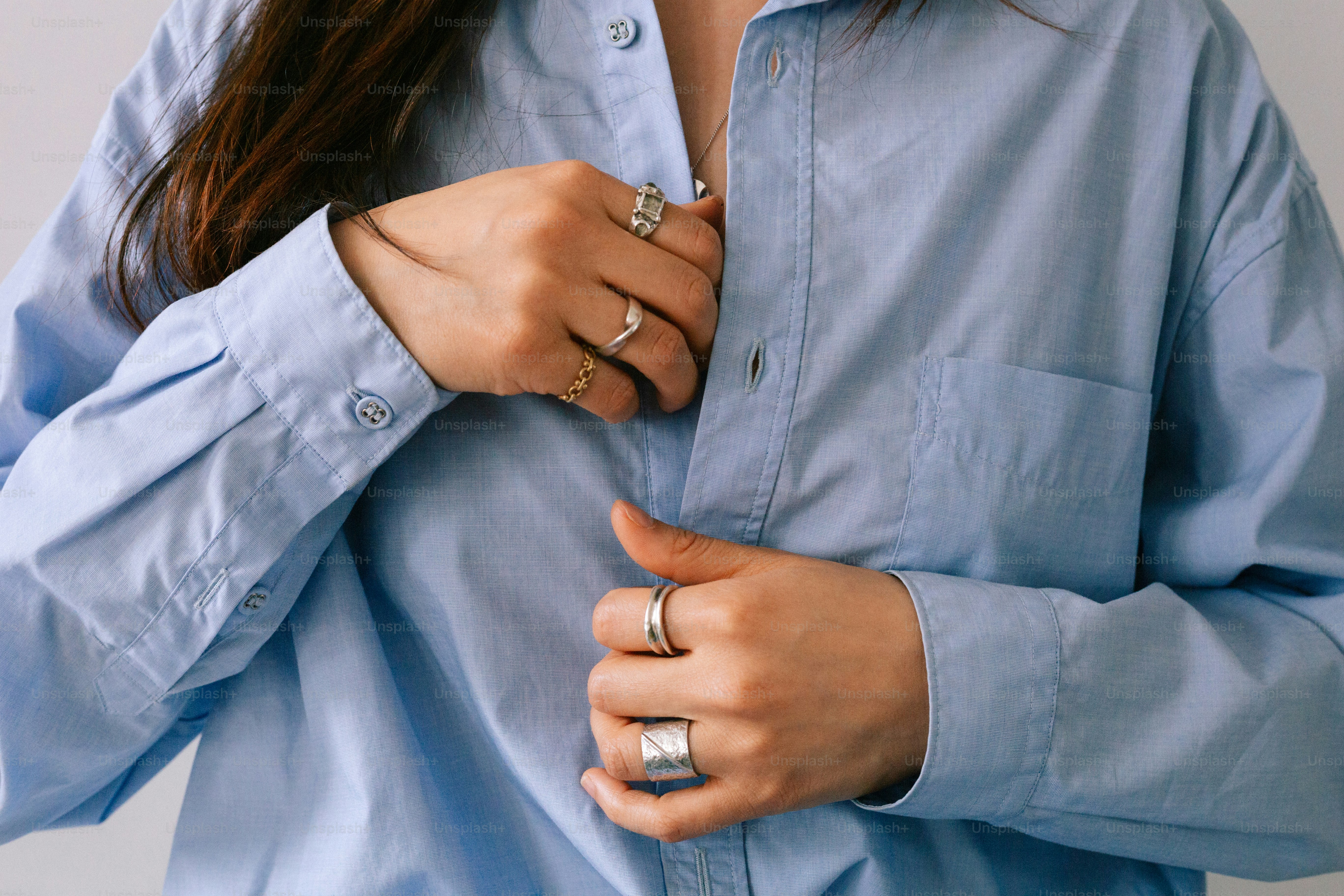 A woman wearing a blue shirt and silver rings