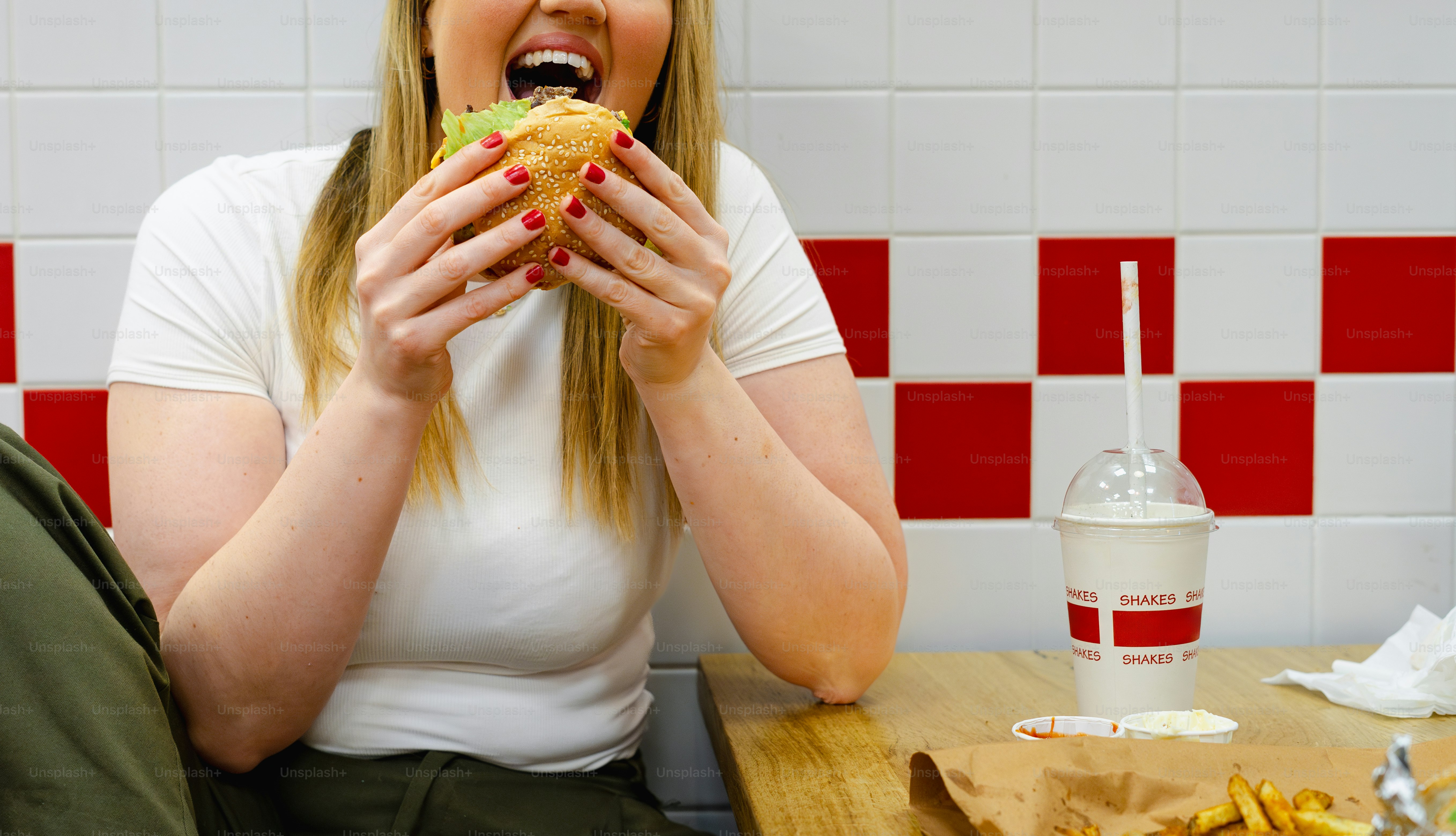 A woman sitting at a table eating a sandwich