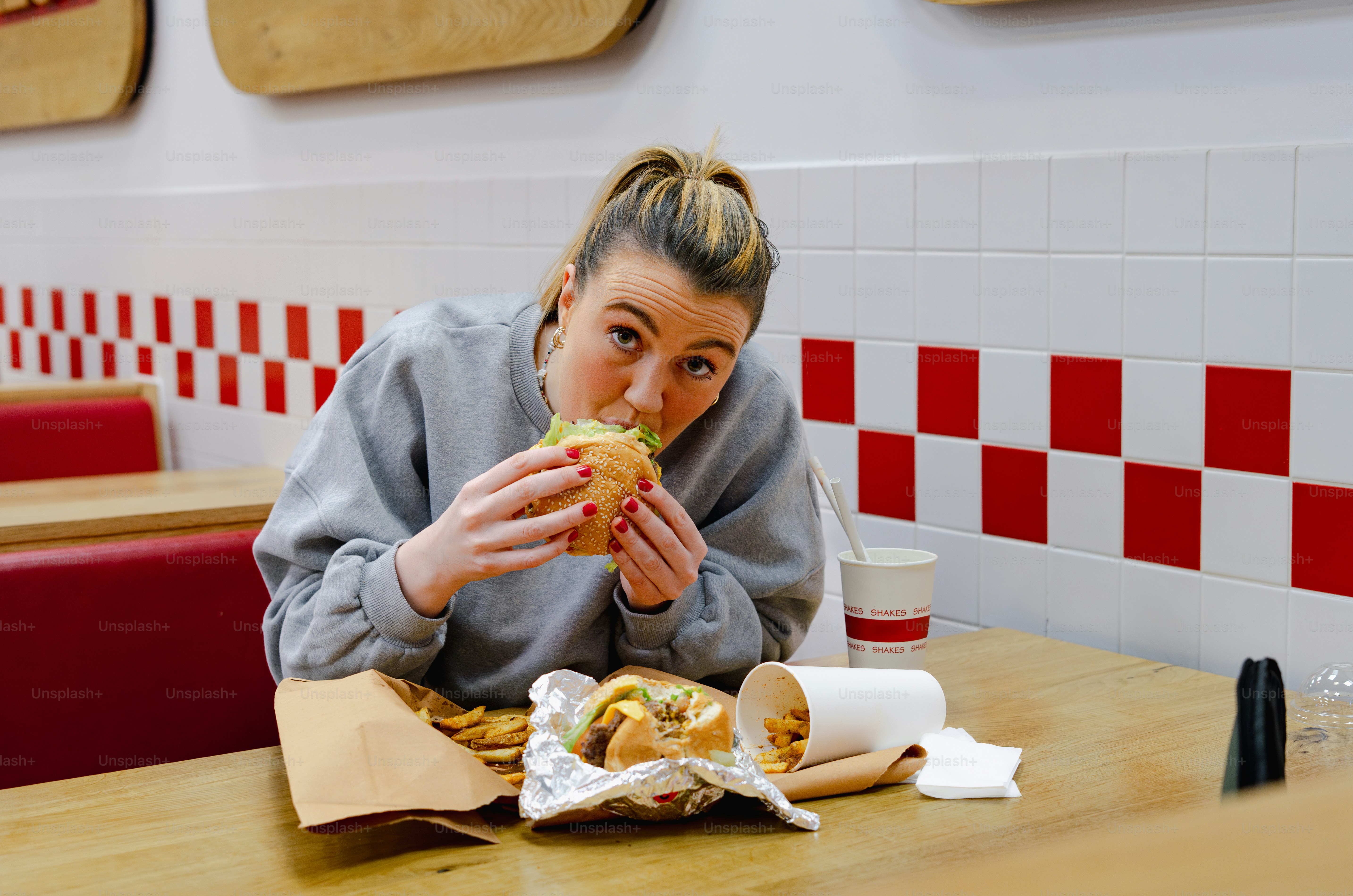 A woman sitting at a table eating a sandwich