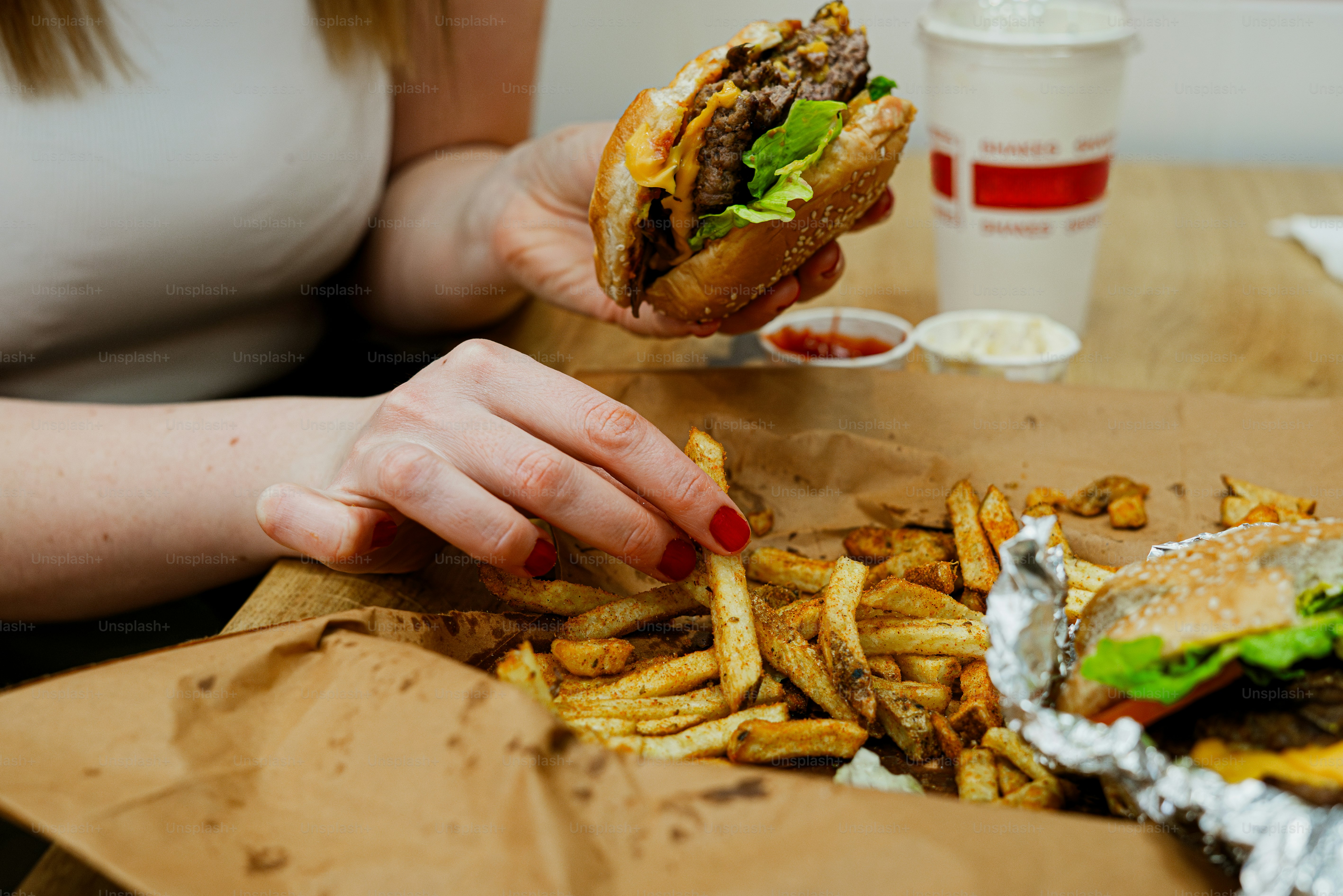 A woman is eating a hamburger and french fries