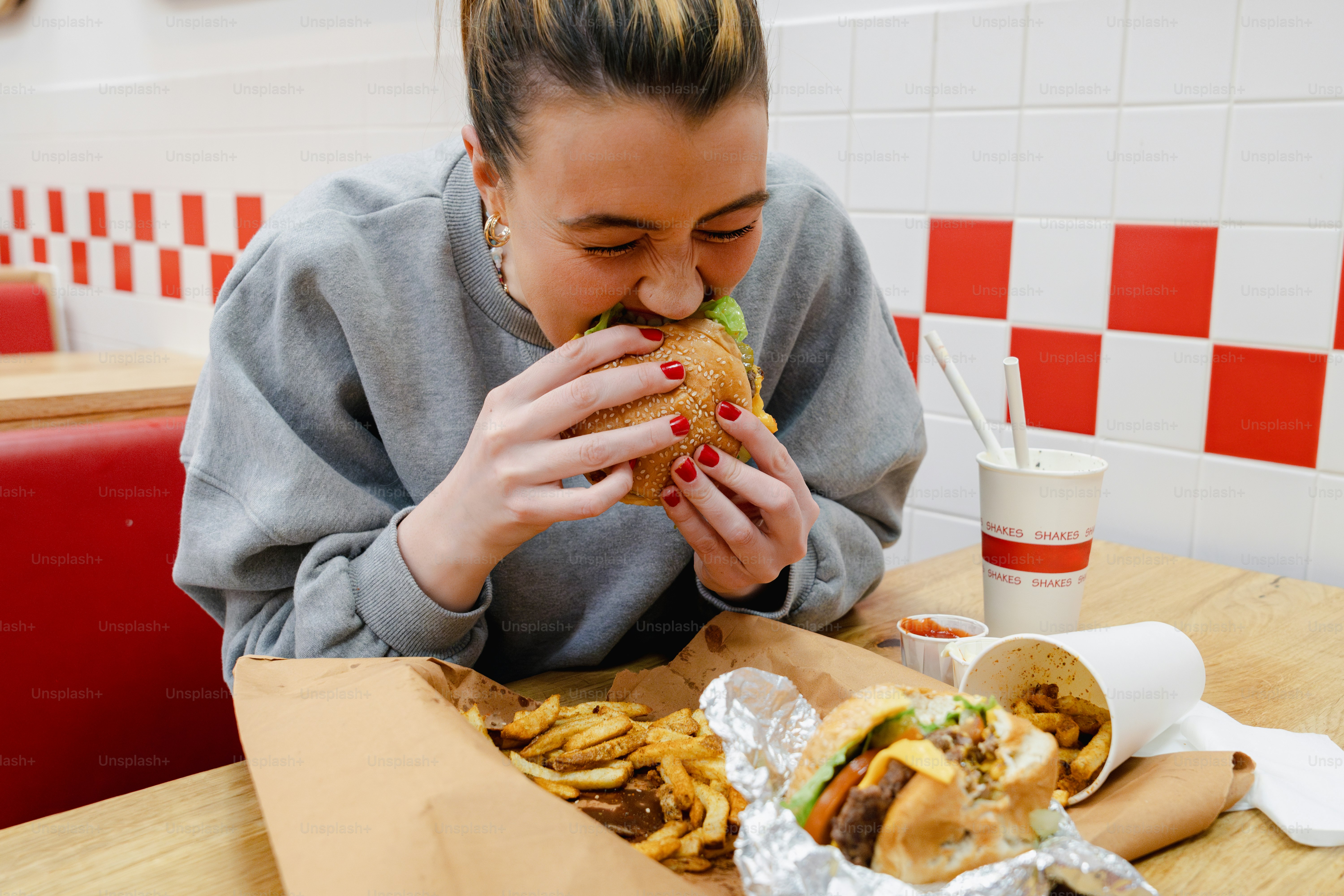 A woman sitting at a table eating a sandwich