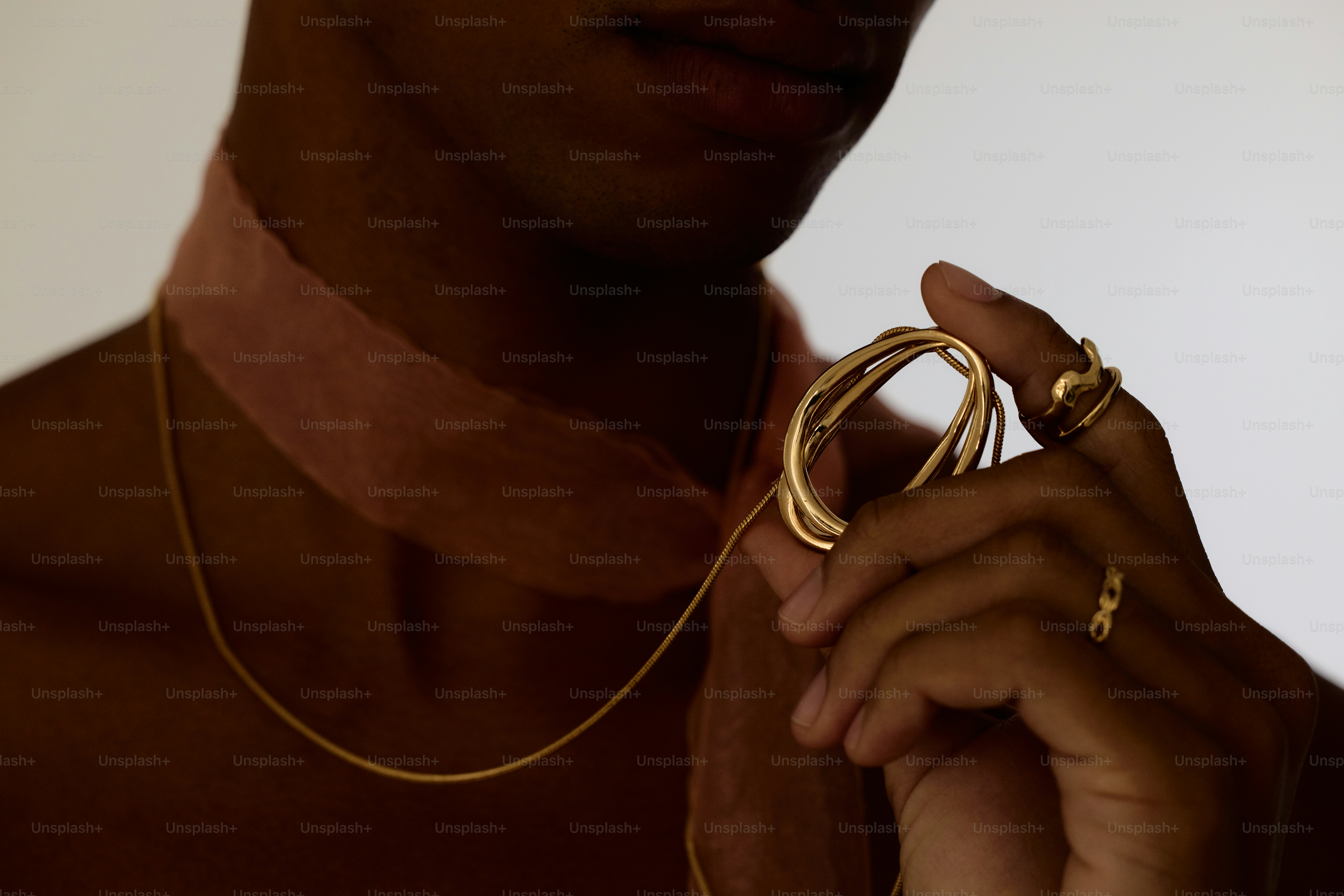 A man wearing a gold necklace holding a gold ring photo – Jewelry Image ...