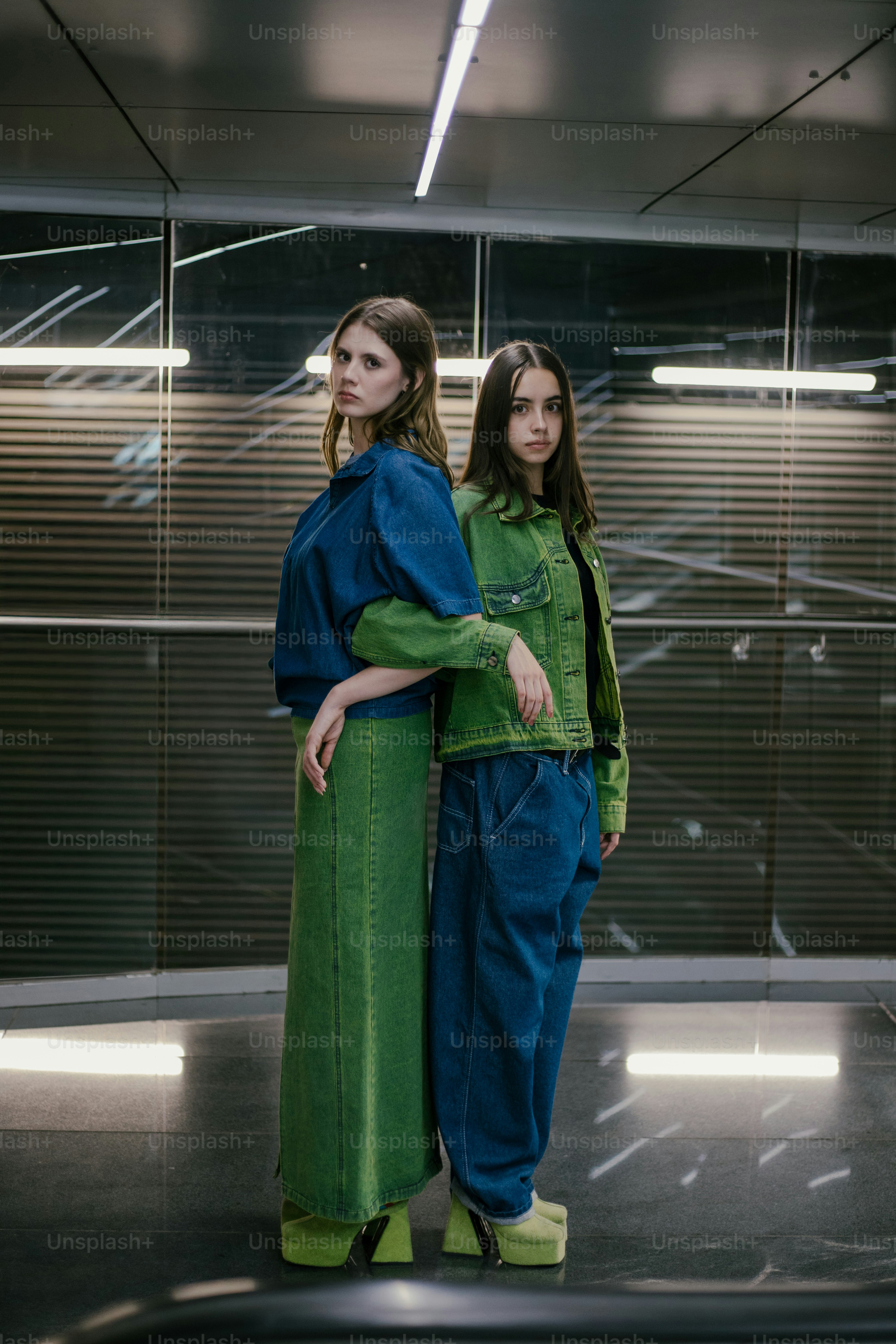 Two women in green and blue outfits standing in a room