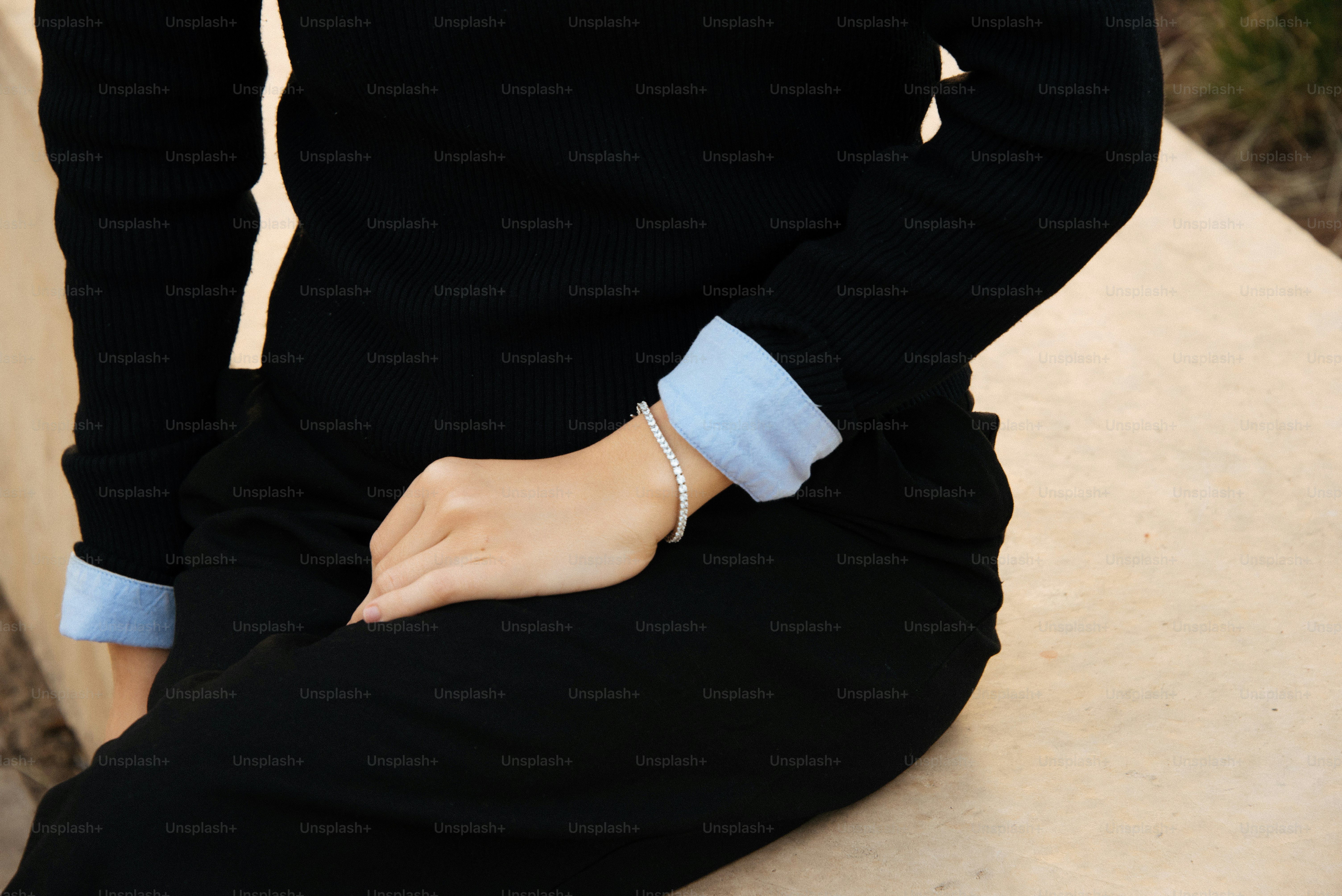 A woman sitting on a ledge with her hands in her pockets