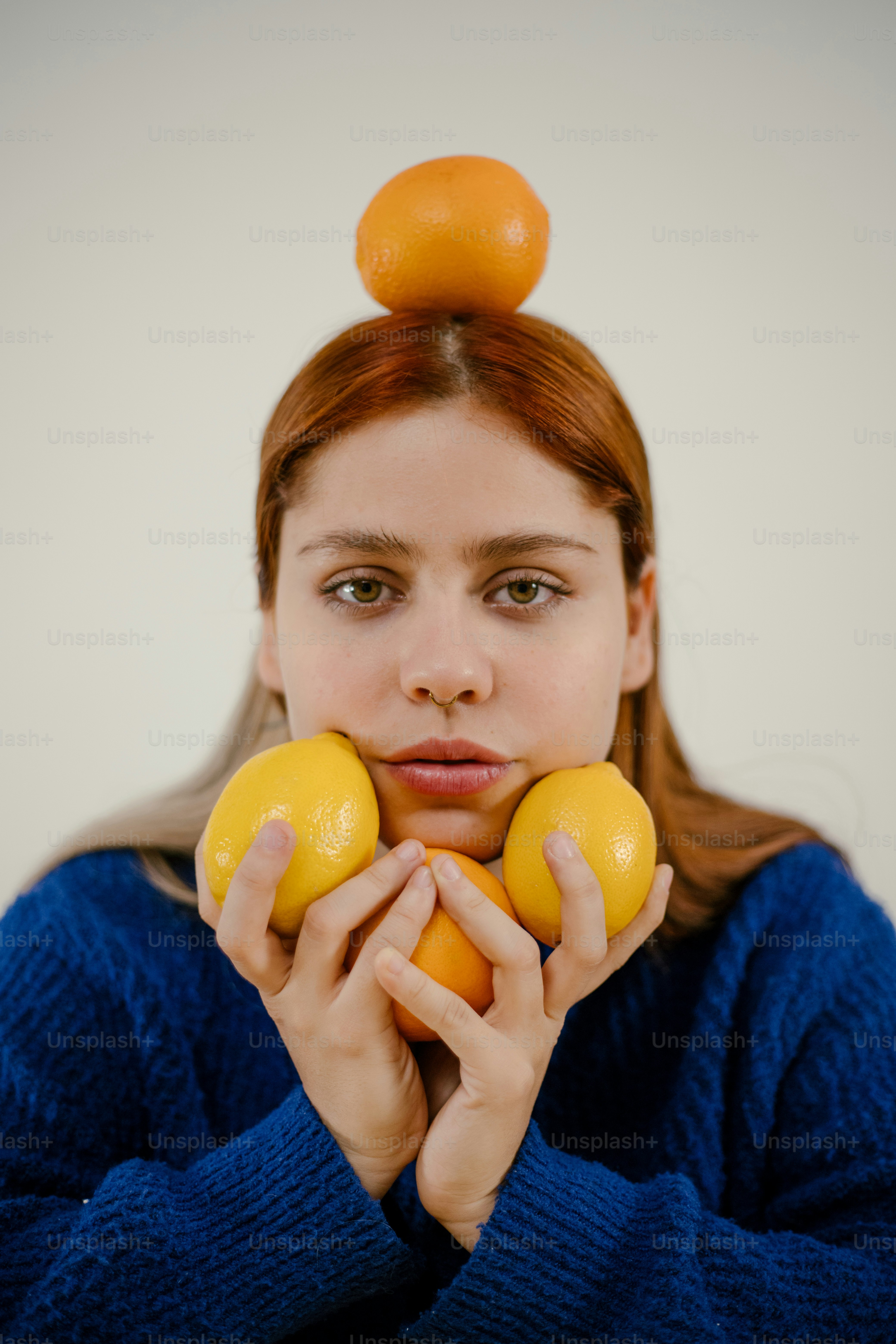 A woman holding two oranges in front of her face