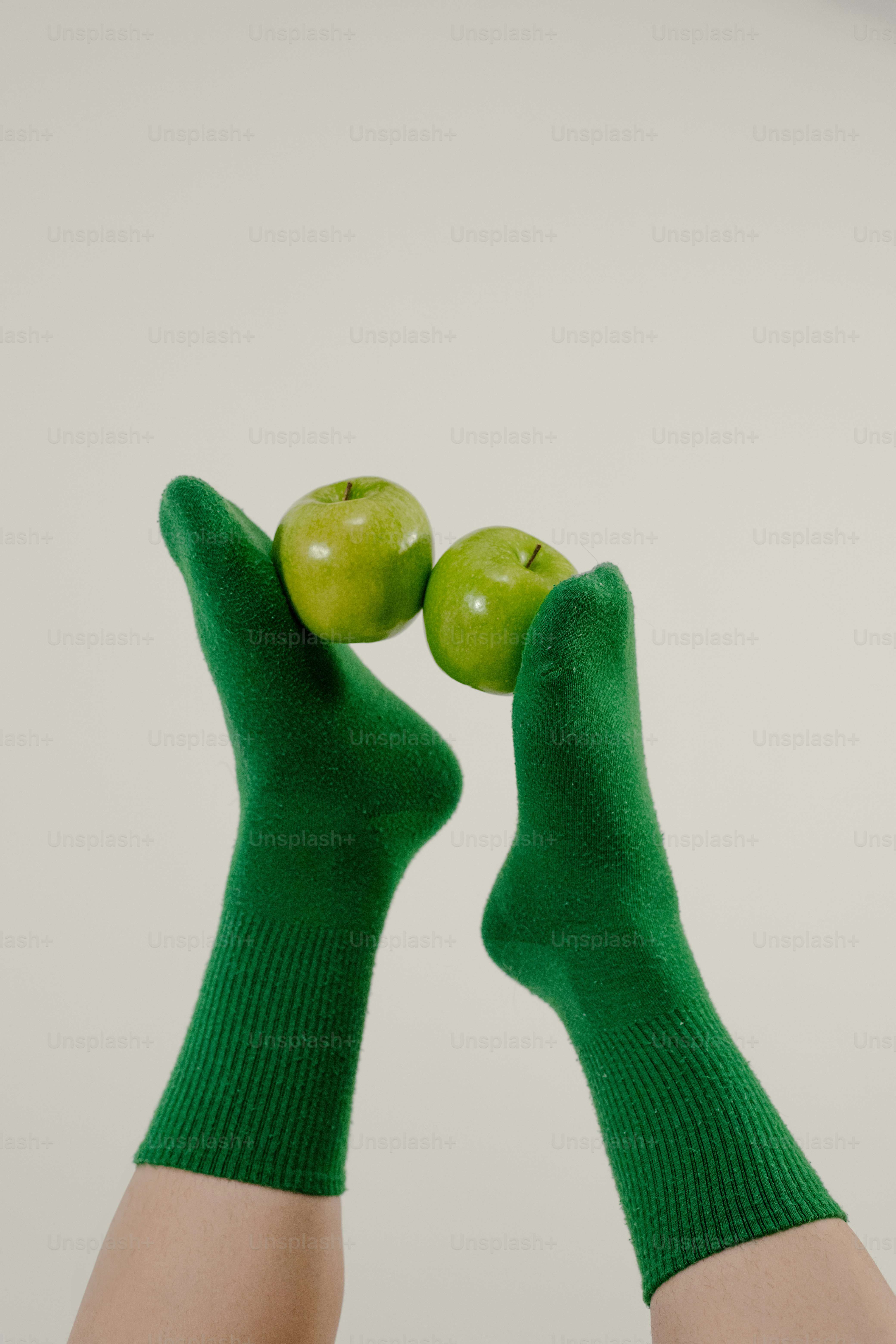 A pair of hands holding two green apples