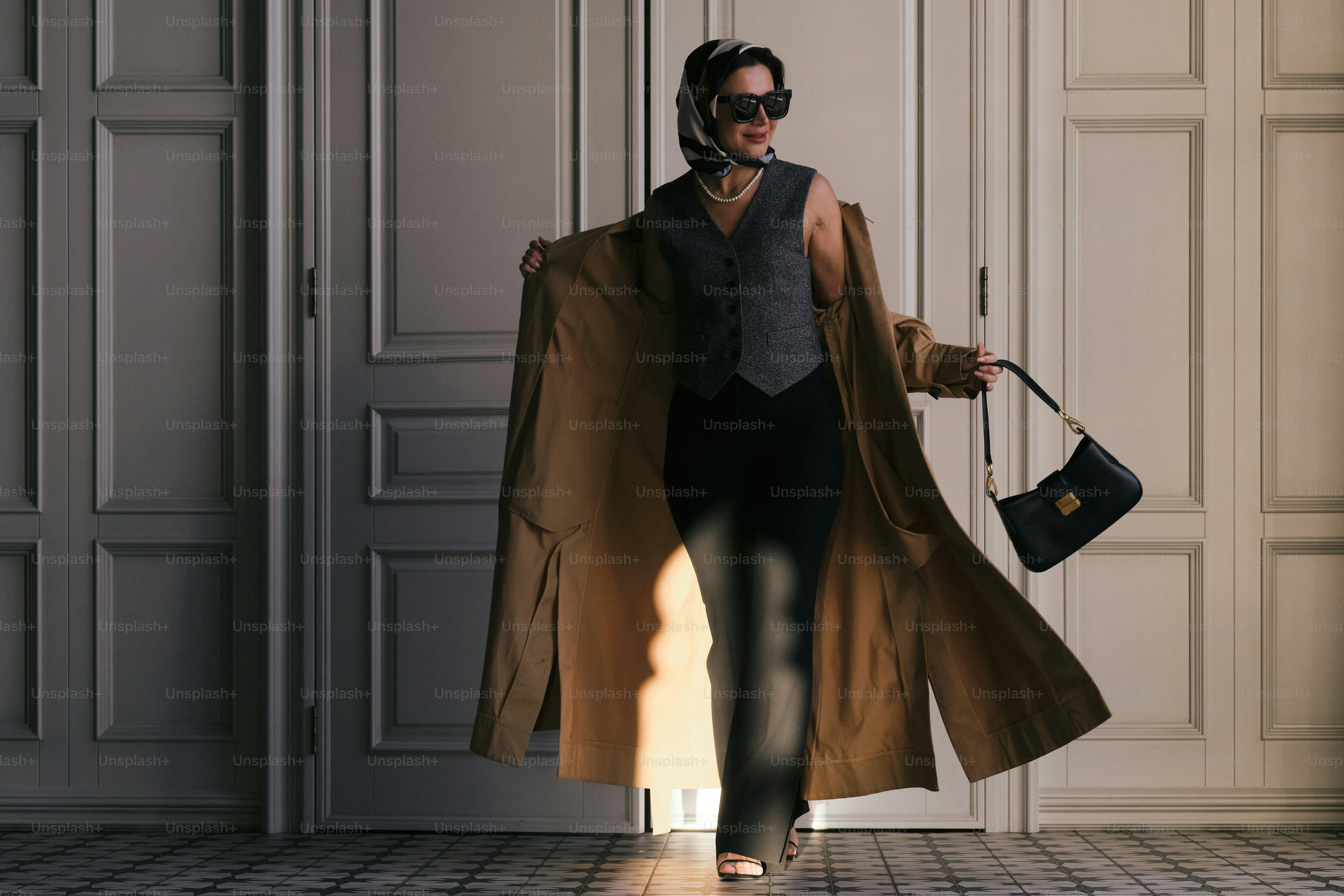 Una mujer con una gabardina sostiene un bolso