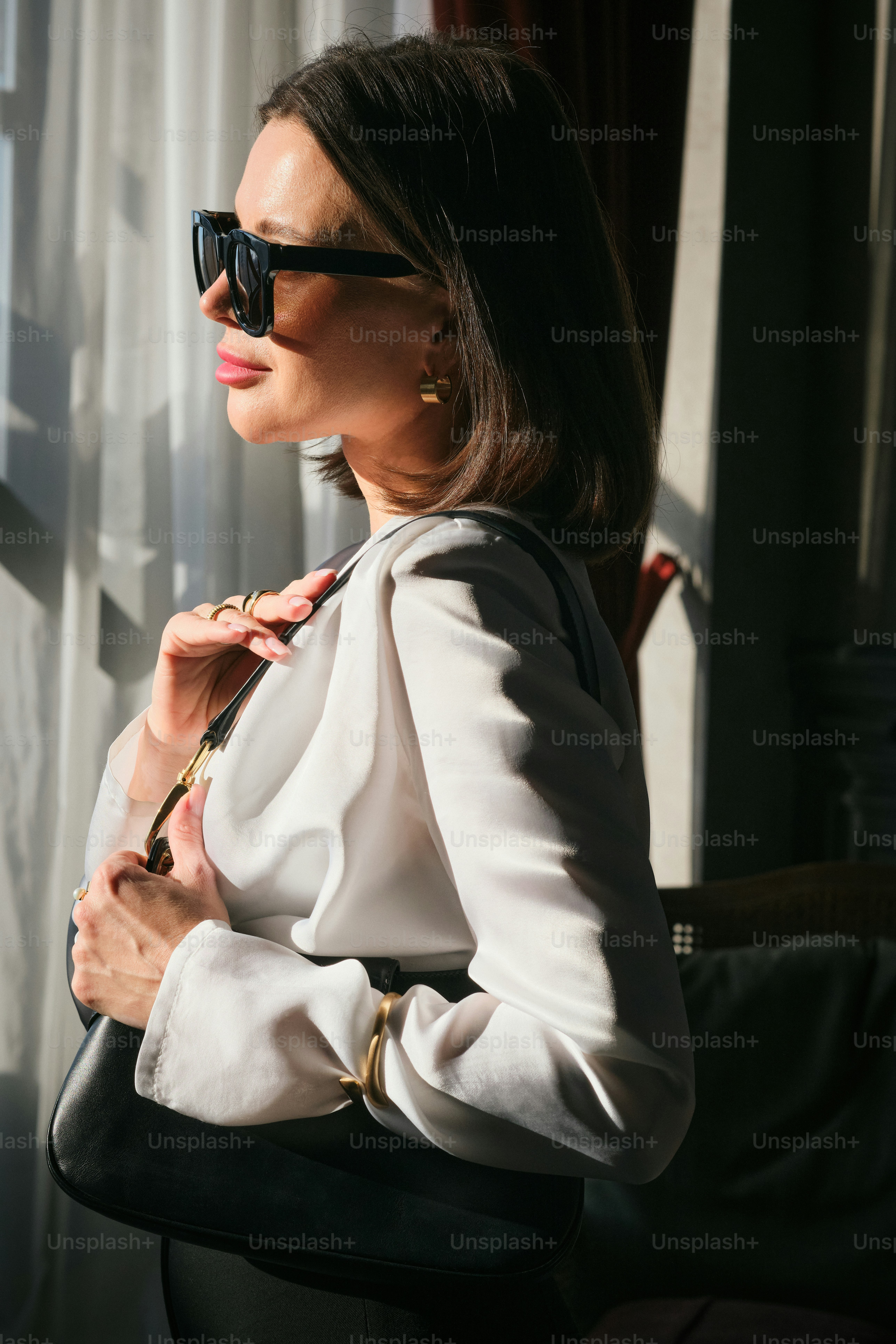 Una mujer de traje y gafas de sol mirando por una ventana