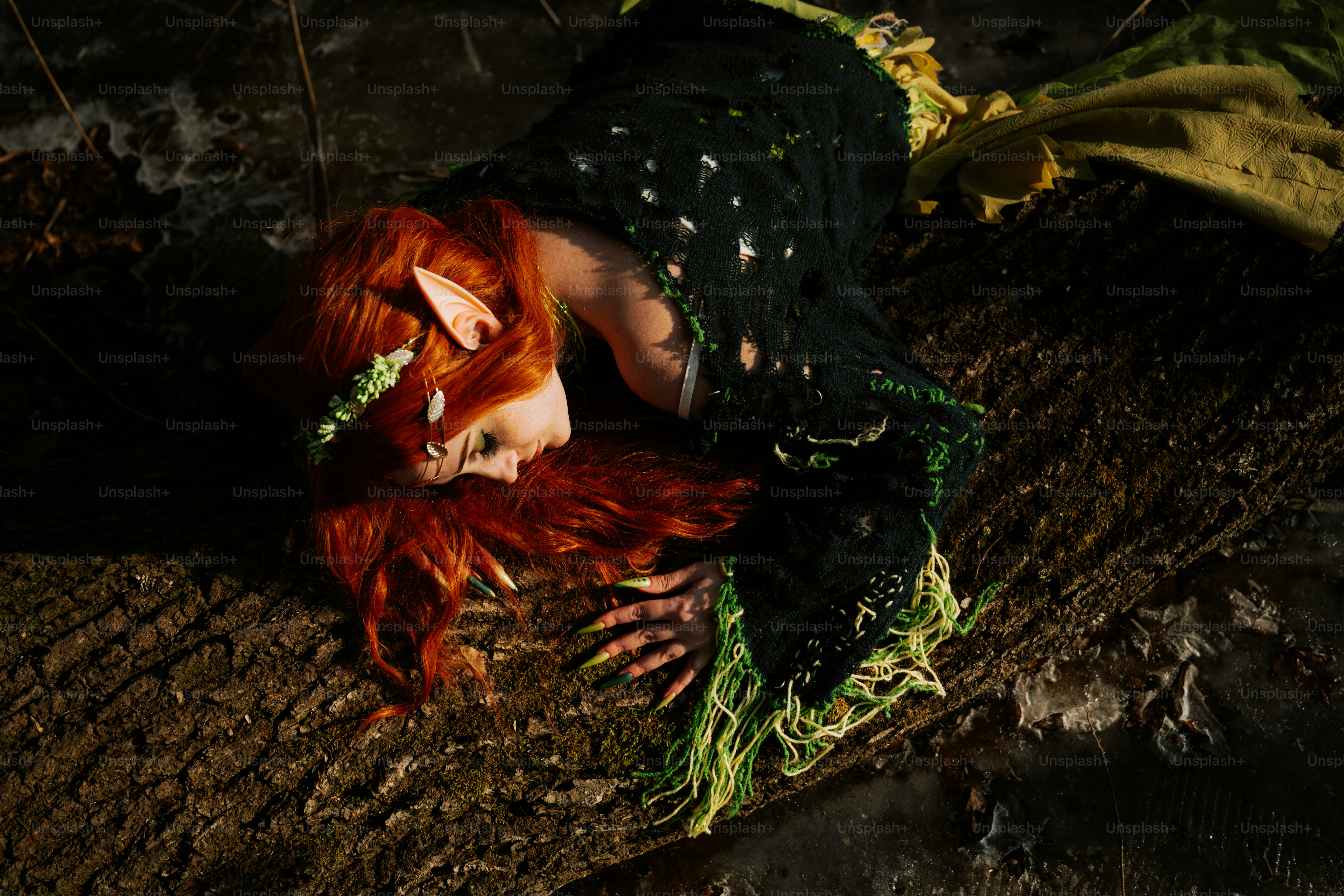 Une femme aux cheveux roux allongée sur un tronc d’arbre