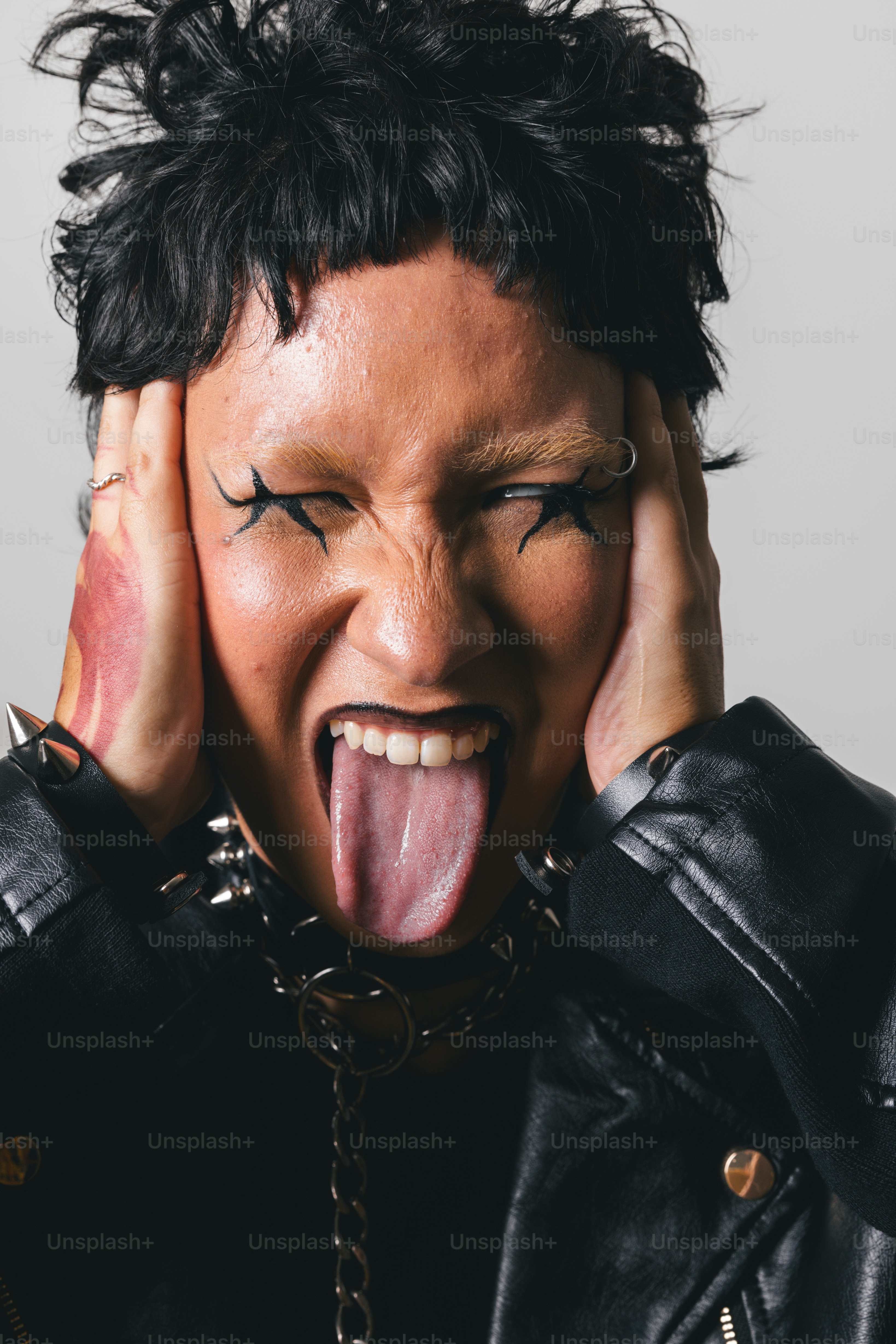 Um homem com a língua pendurada para fora com as mãos no rosto