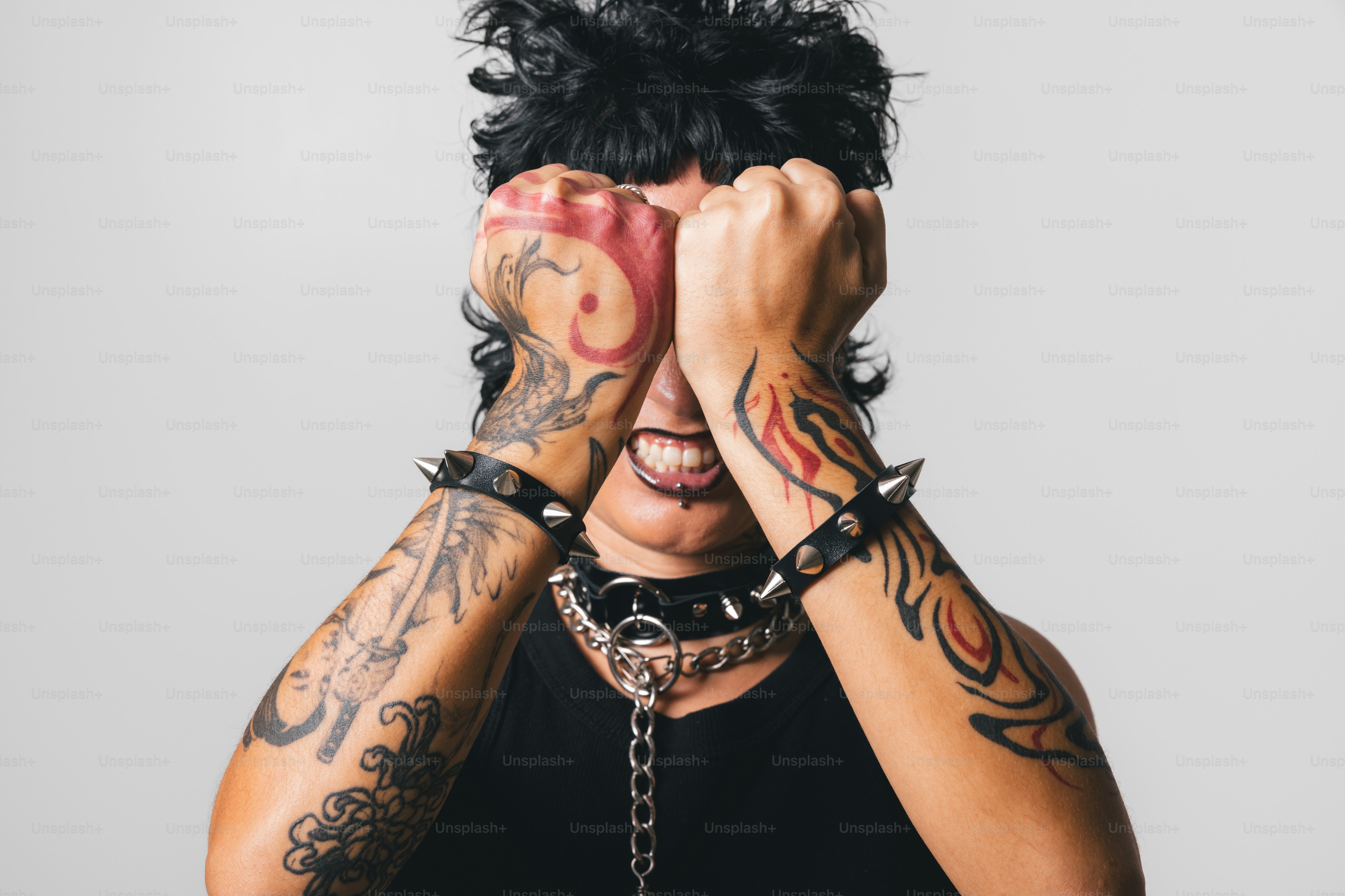 Um homem com tatuagens cobrindo seu rosto com as mãos