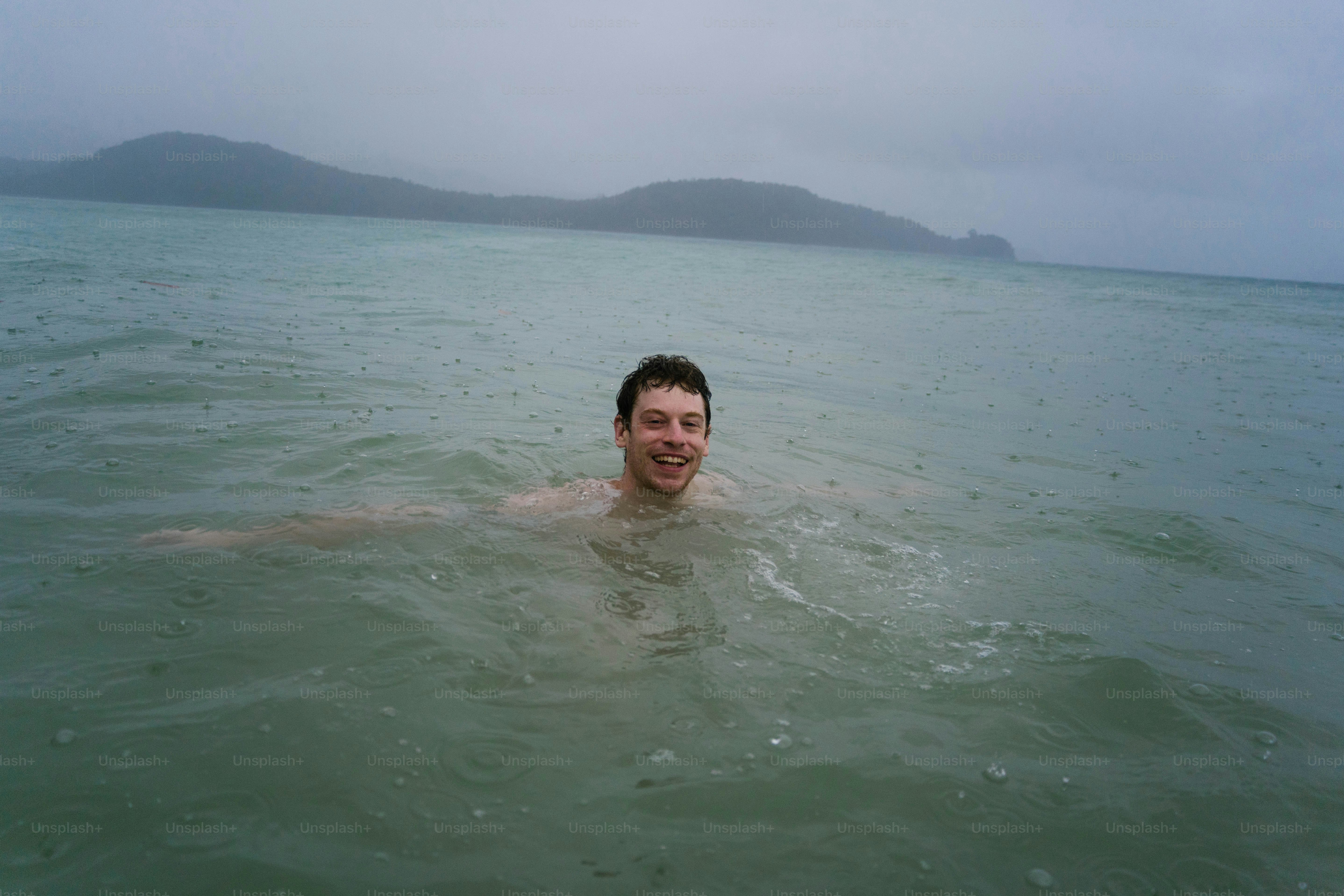 Ein Mann, der an einem bewölkten Tag im Meer schwimmt