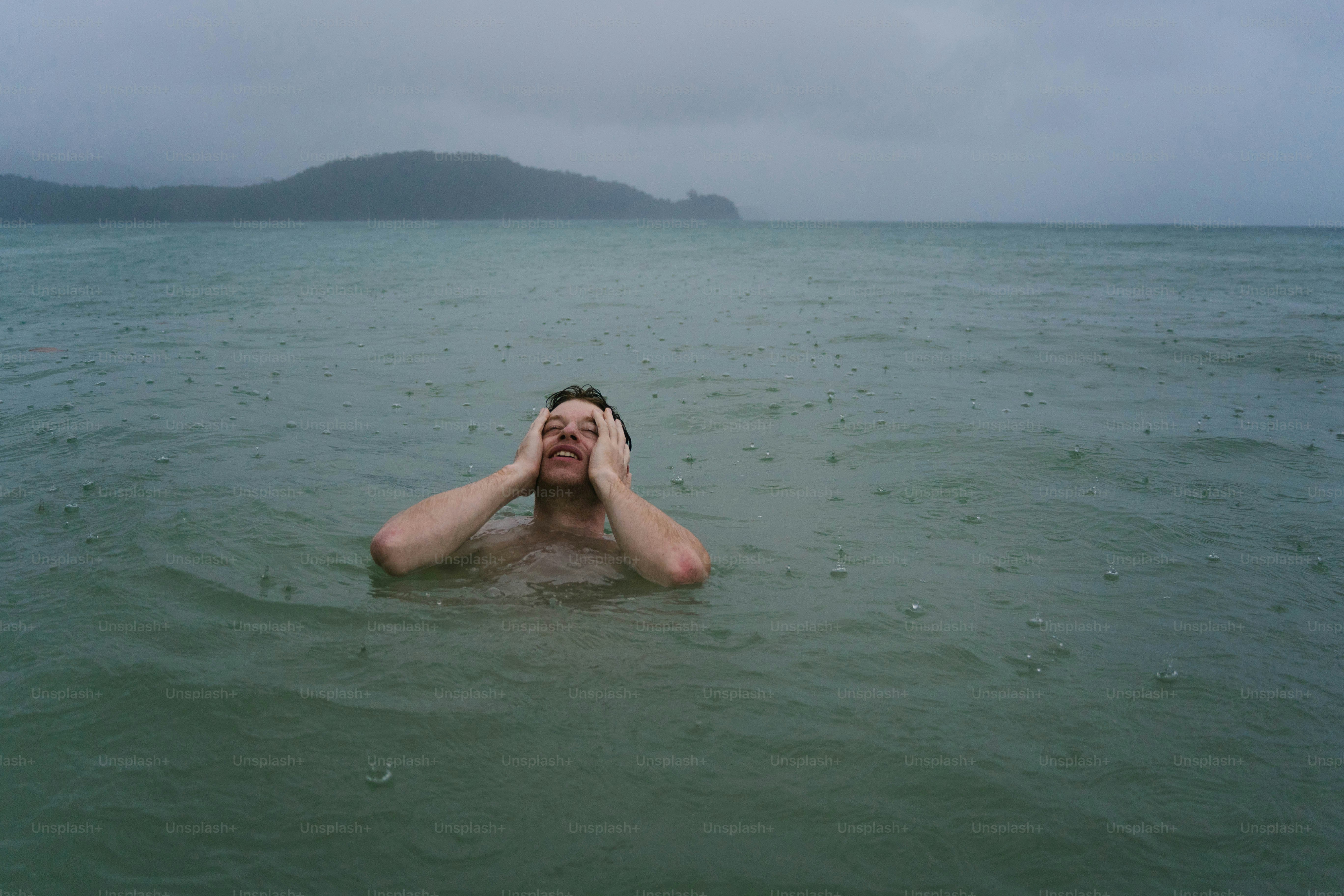Ein Mann, der mit dem Kopf in den Händen im Ozean treibt