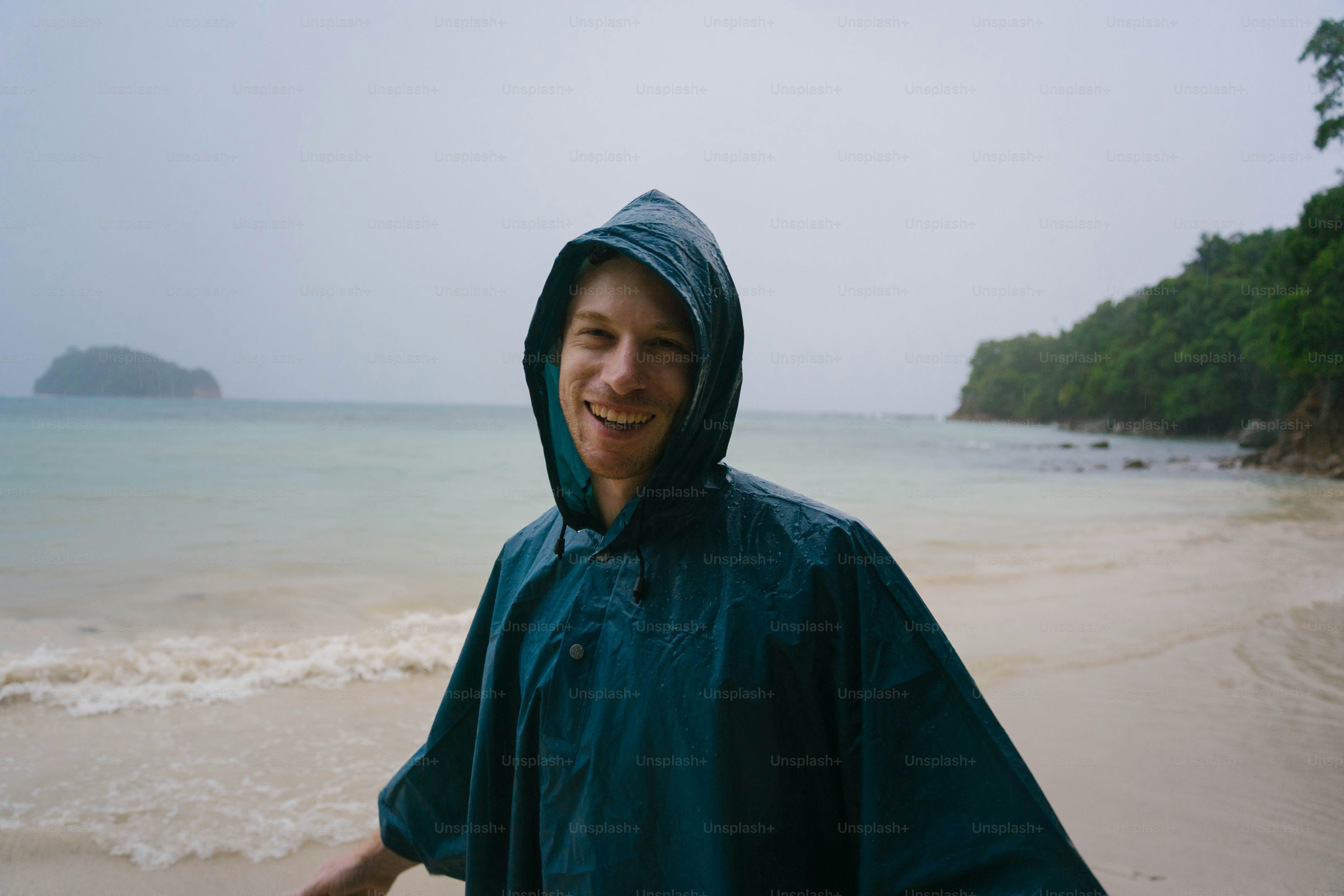 Ein Mann, der mit einem Regenmantel an einem Strand steht