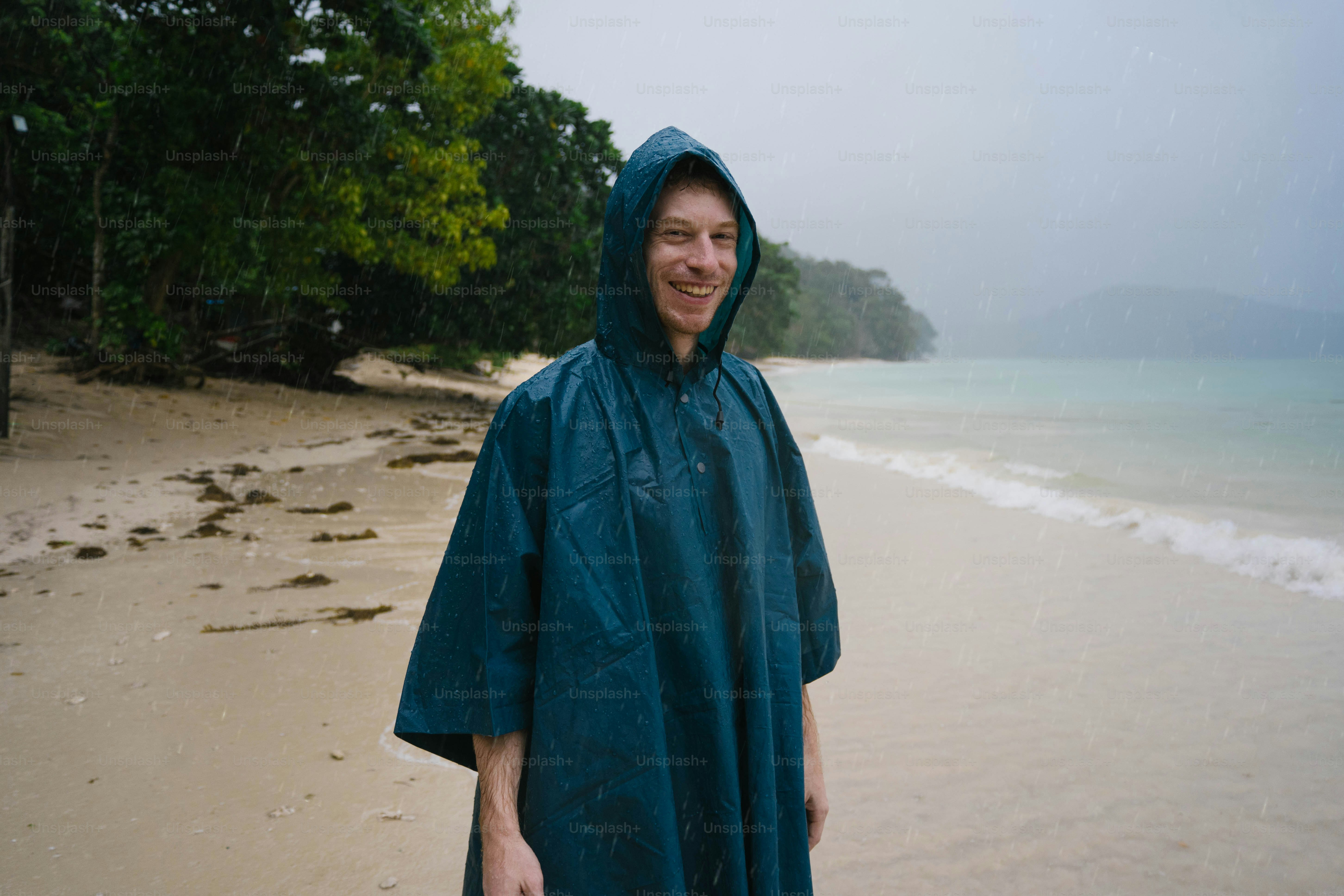 Ein Mann, der mit einem Regenmantel an einem Strand steht