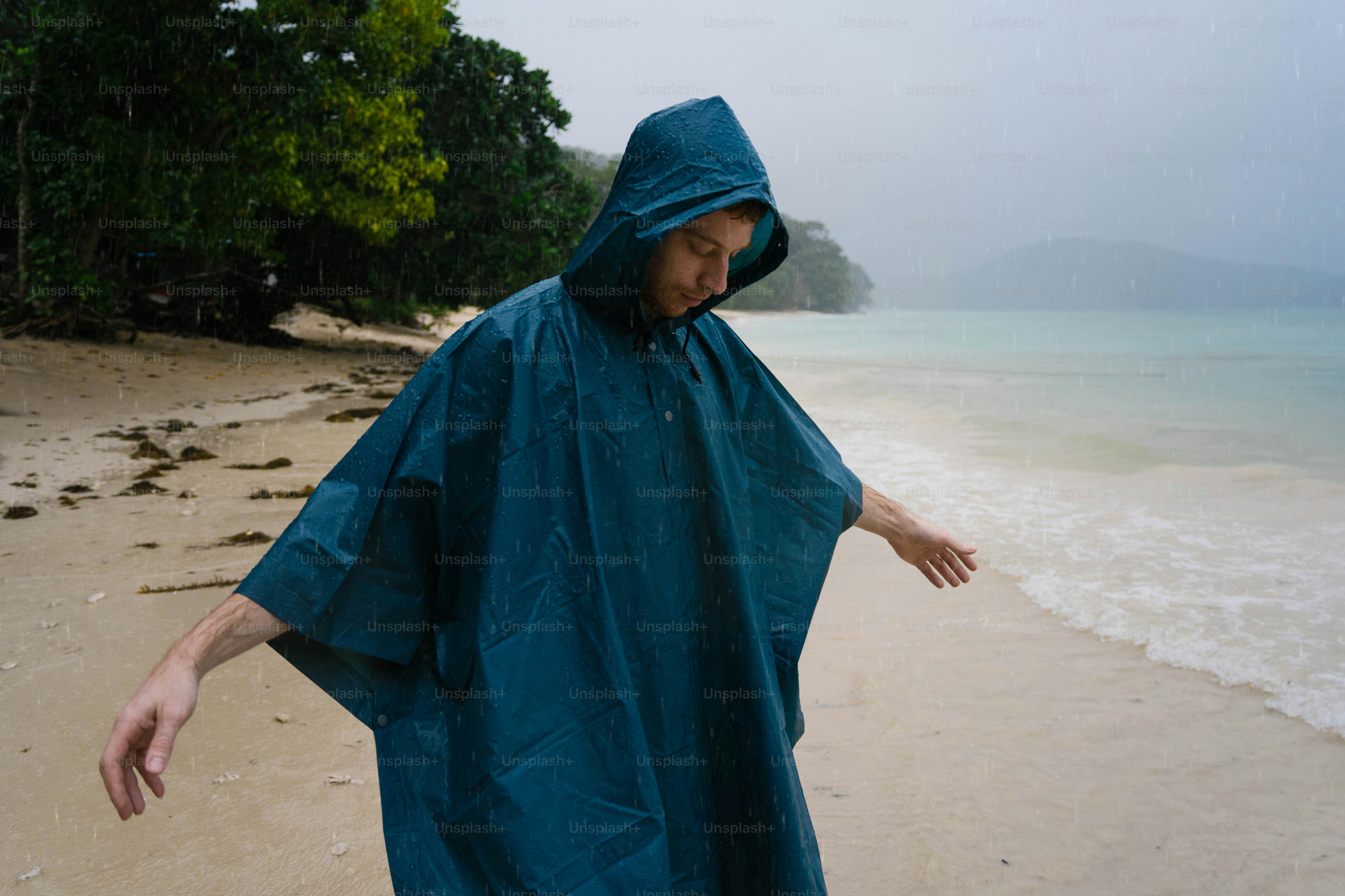 A man in a raincoat walking on a beach