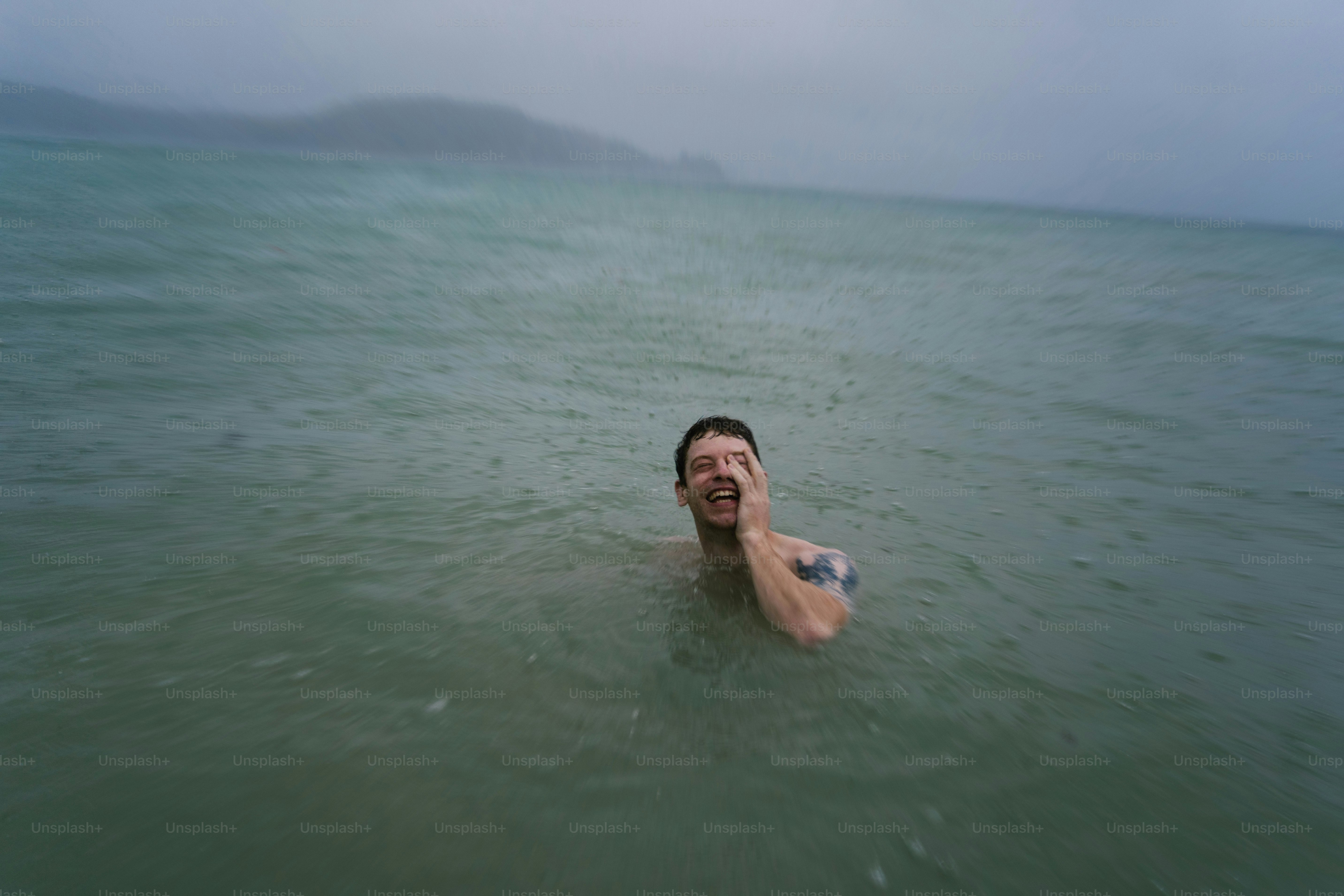 Ein Mann, der an einem bewölkten Tag im Meer schwimmt