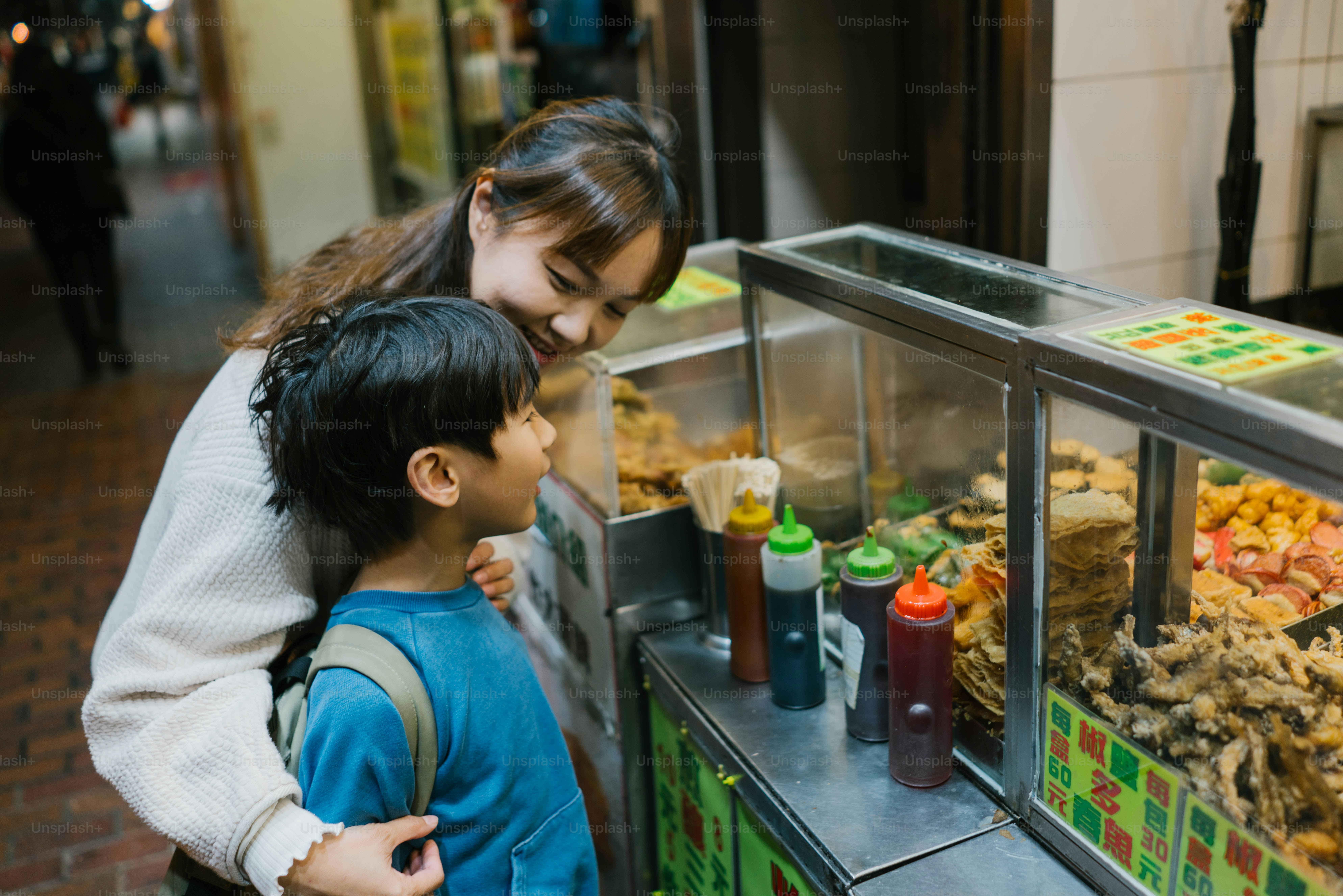 A couple of kids standing in front of a display of food