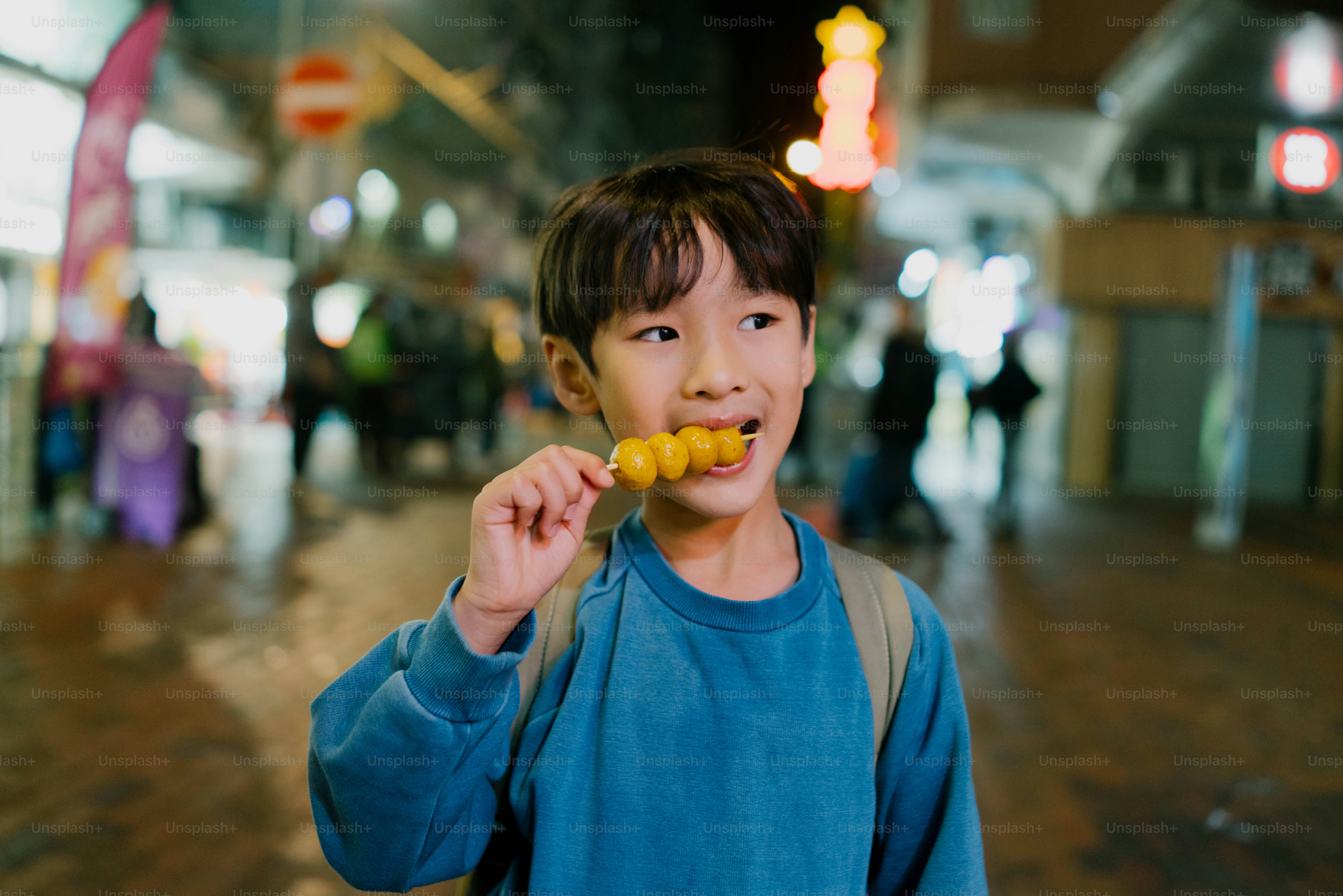 A young boy holding a banana in his mouth