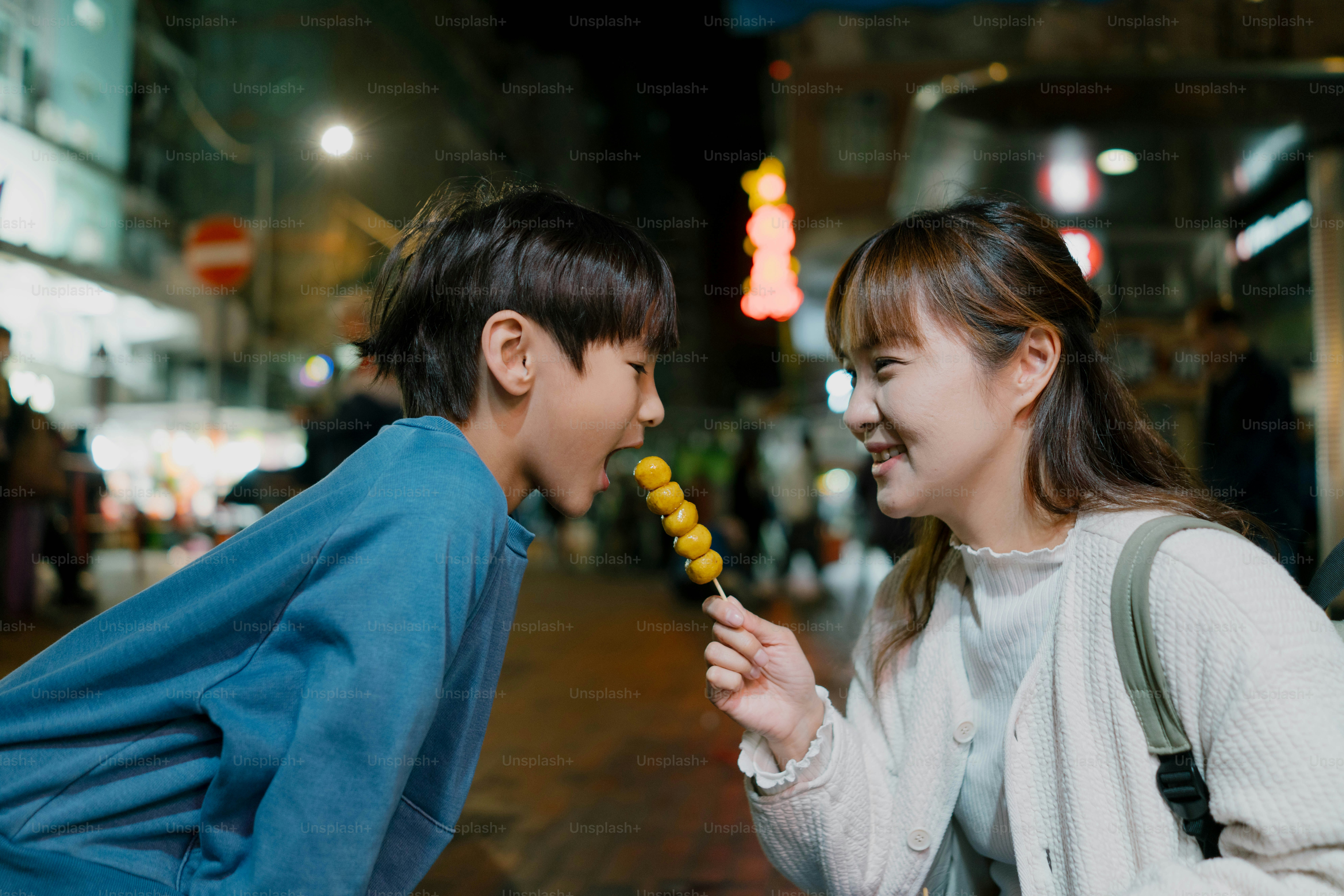 A boy and a girl sharing a corn on the cob