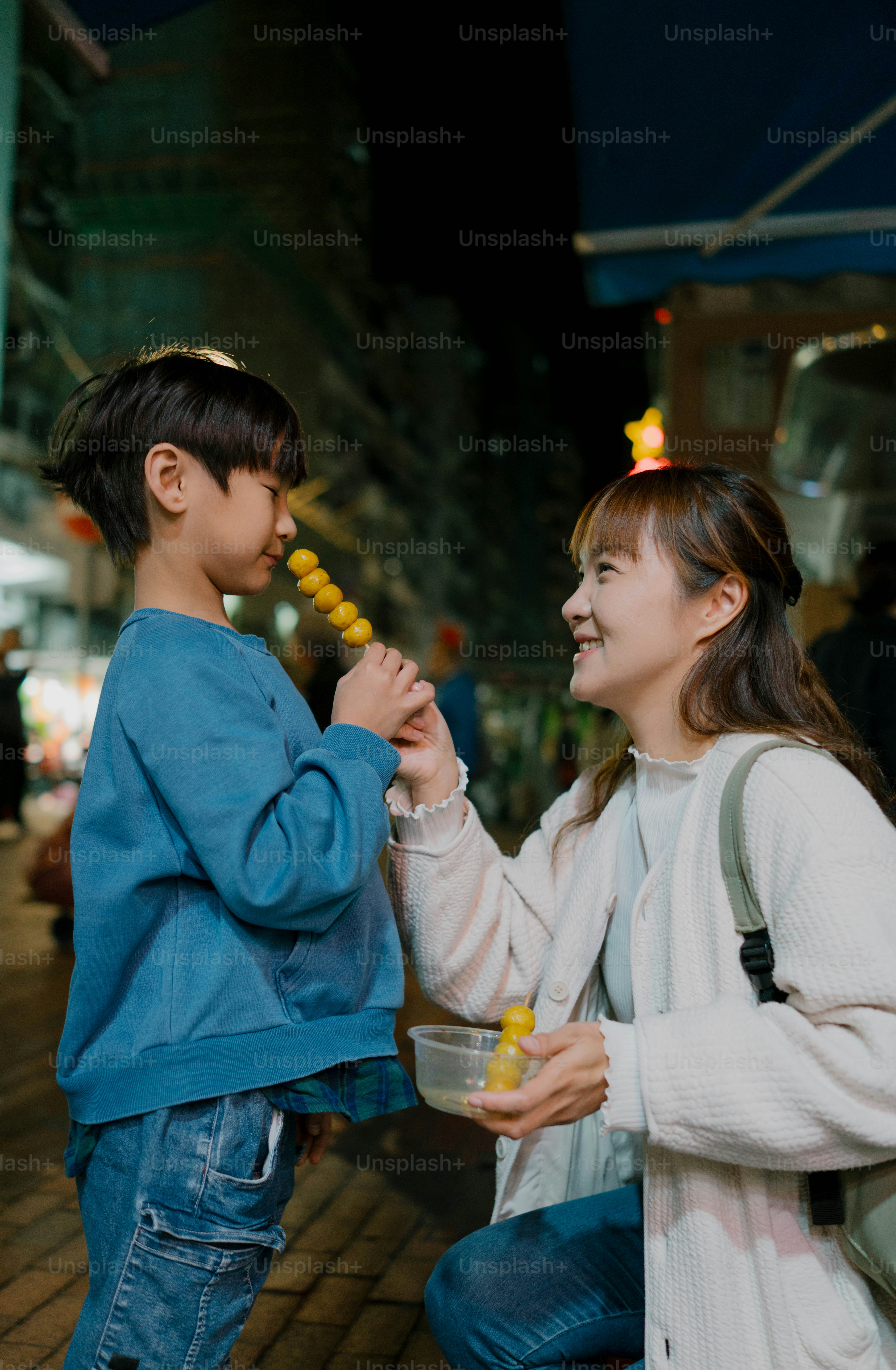 A woman holding a child's hand in a city at night