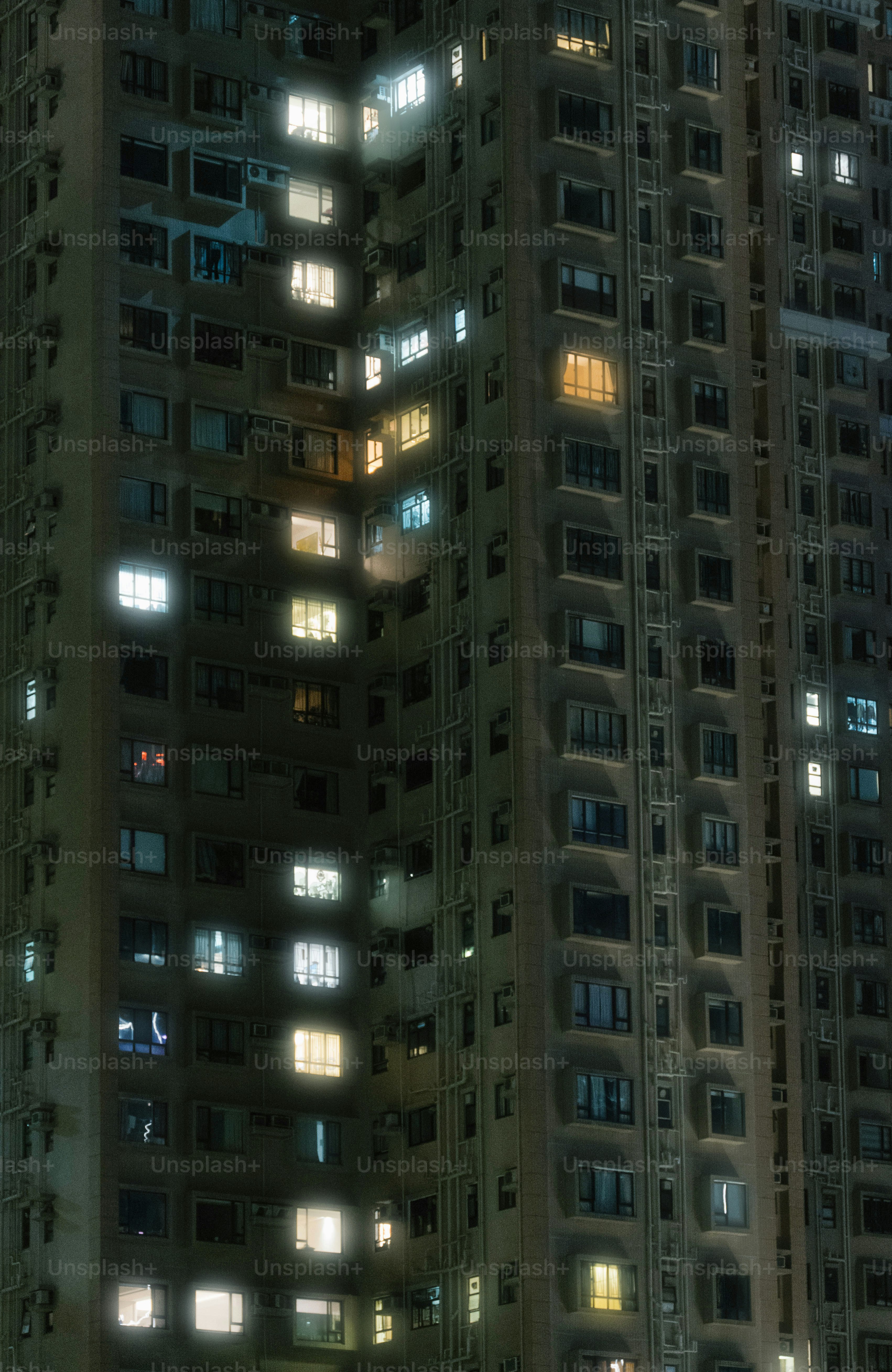 A tall building with lots of windows lit up at night