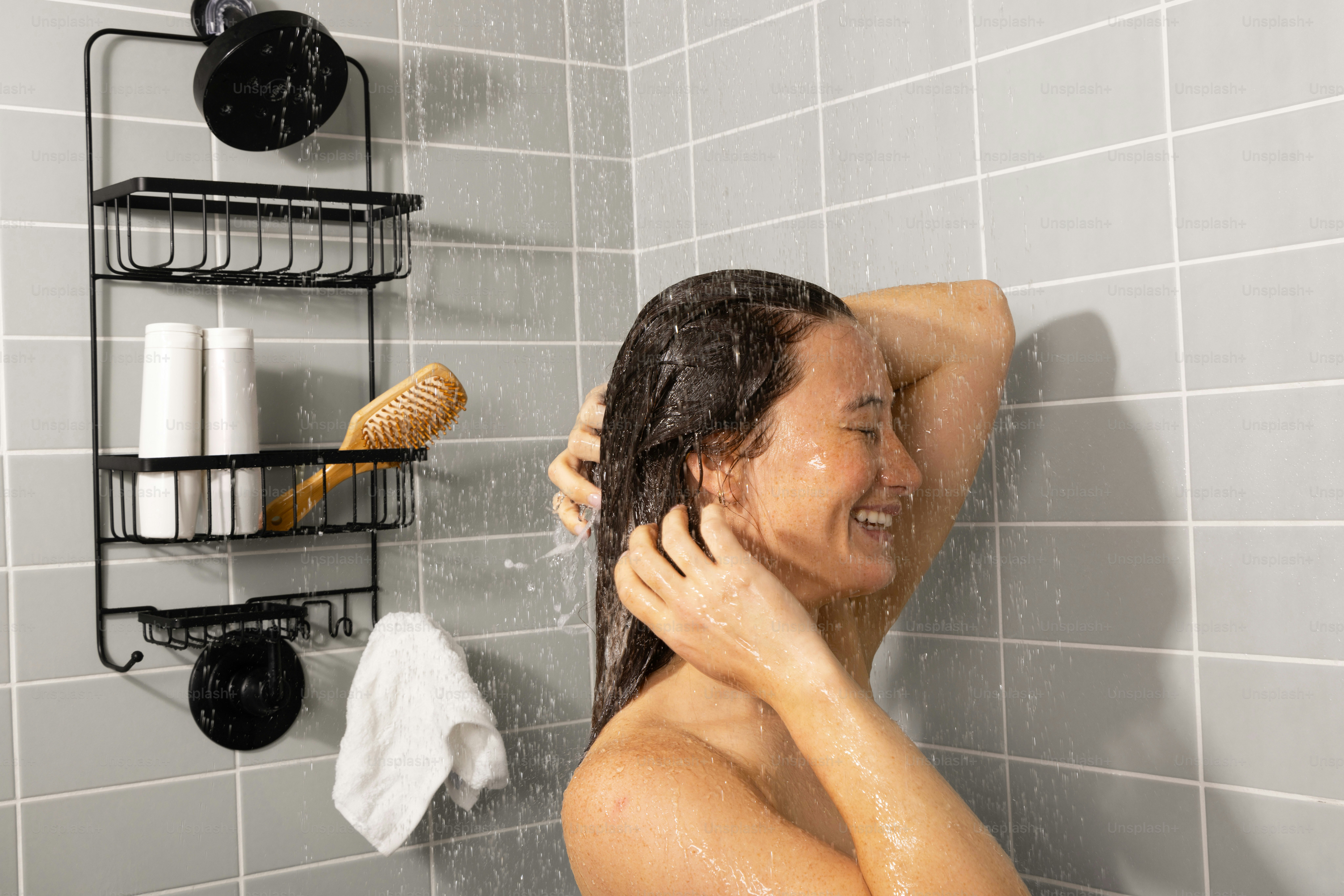Frau wäscht sich unter der Dusche die Haare.