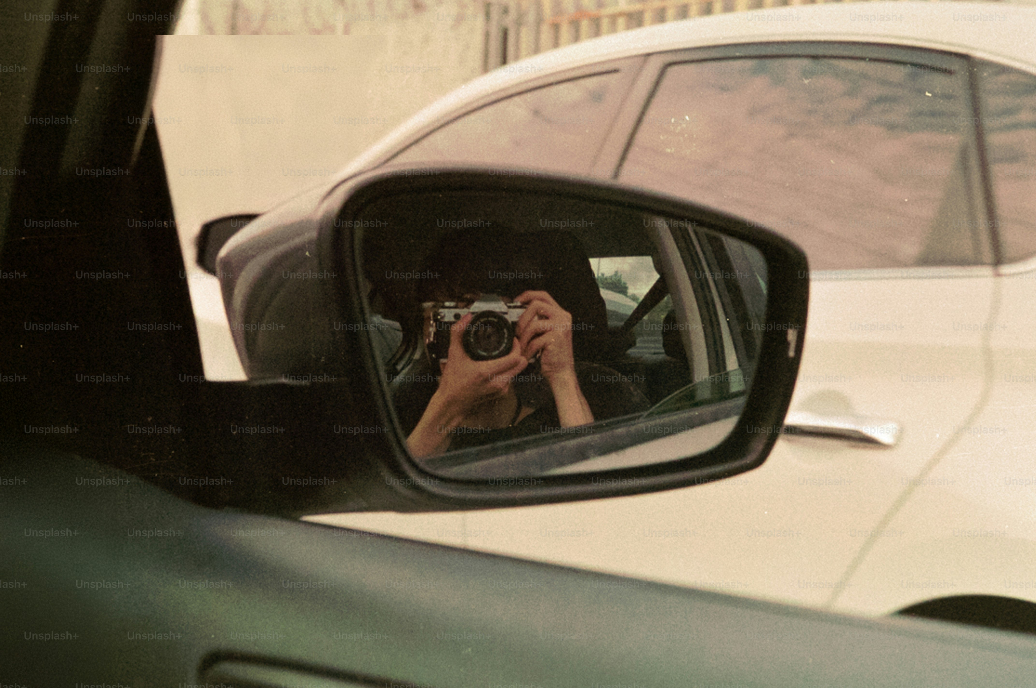 A person is taking a photo in the rearview mirror.