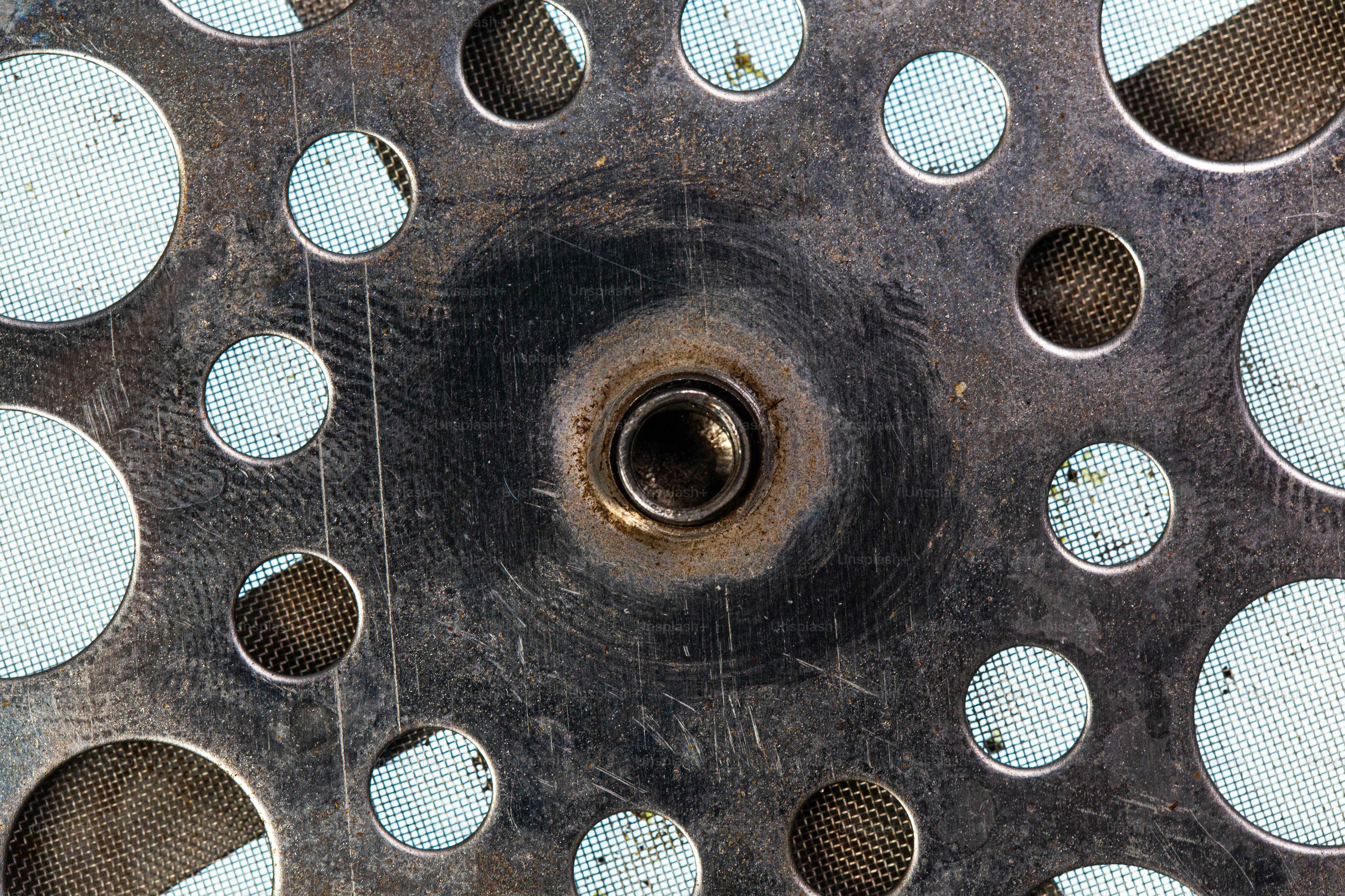 Metal surface with holes and a central bolt.