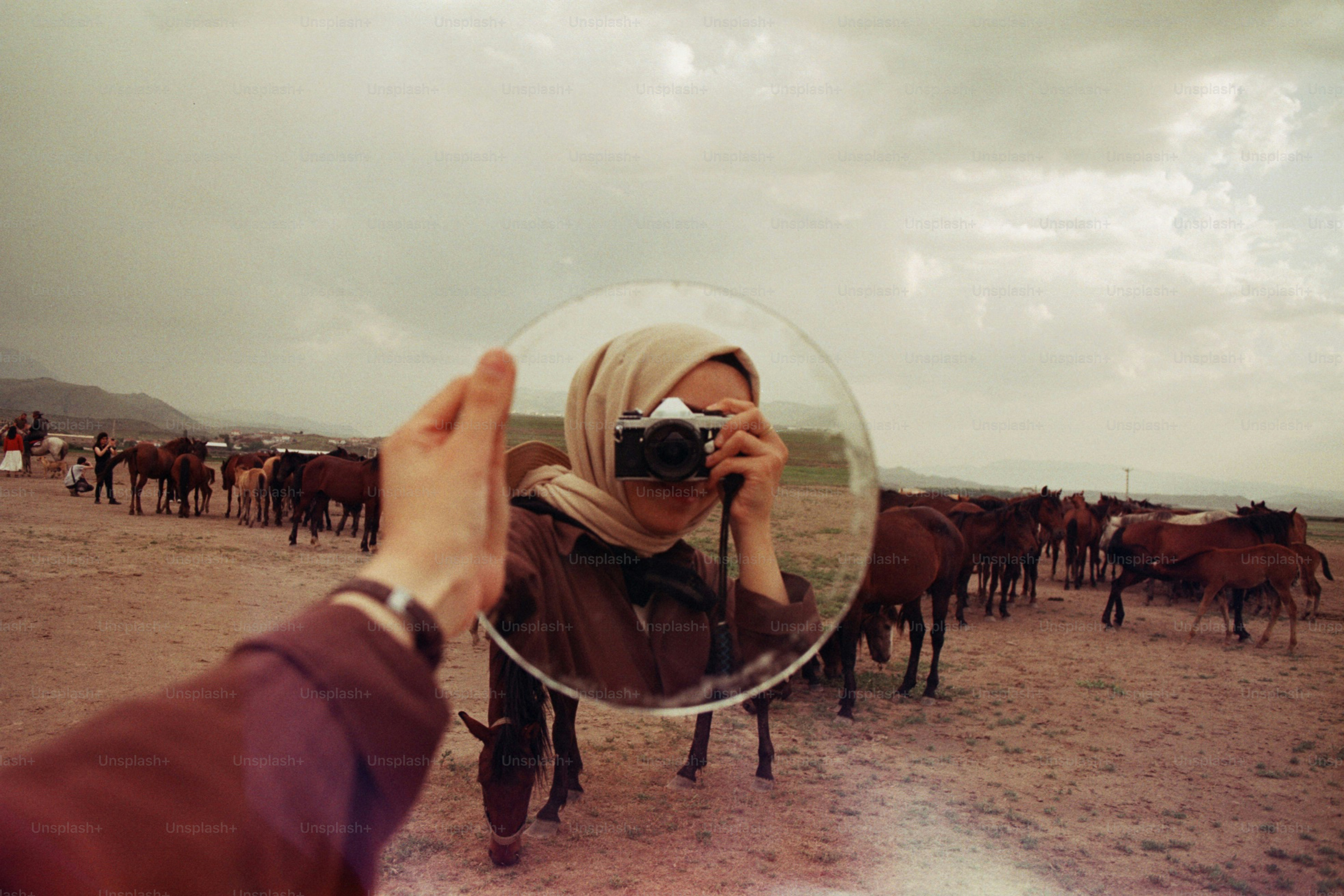 A woman photographs with a mirror in the desert.
