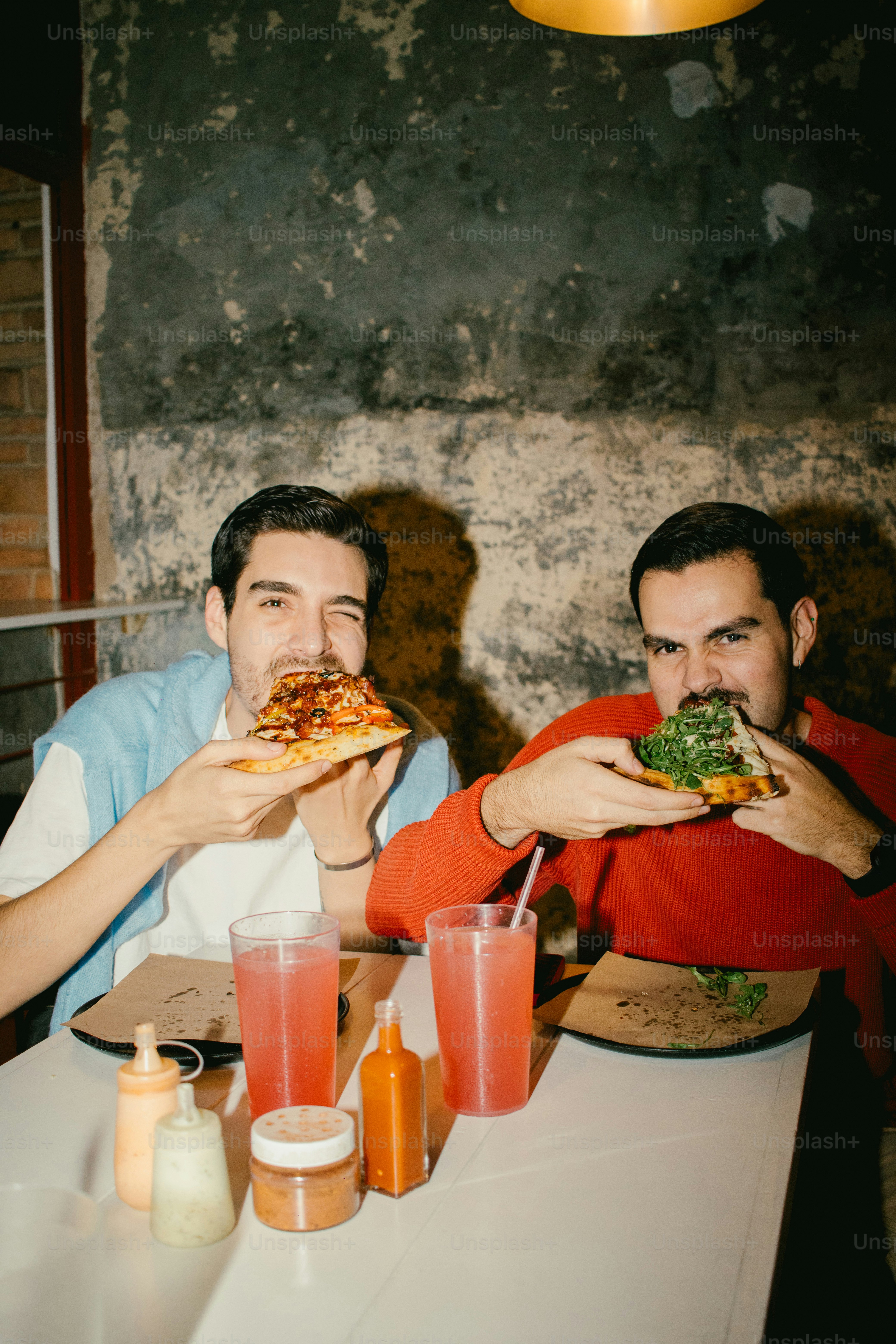 Deux amis mangent une pizza ensemble dans un restaurant.