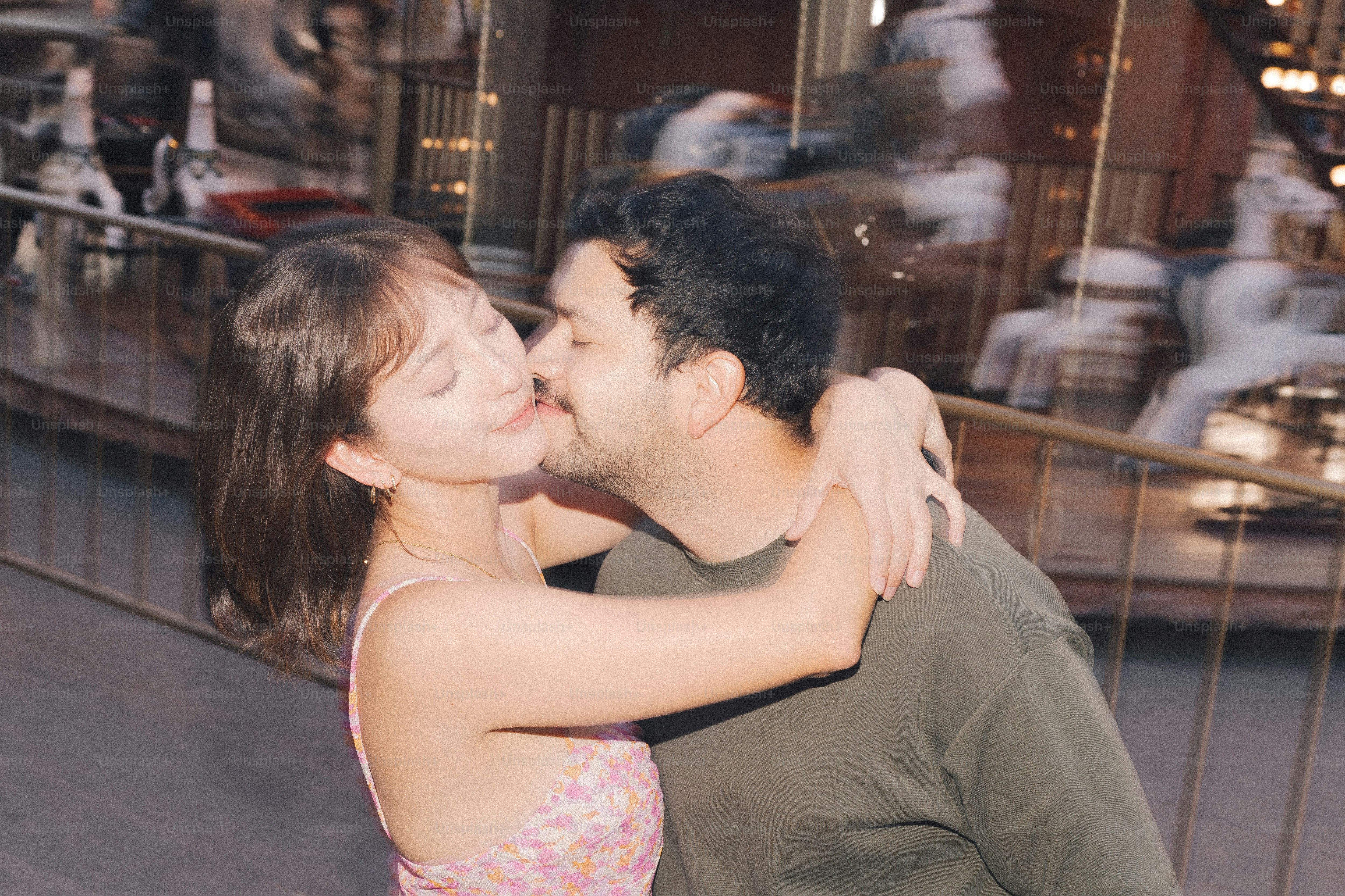 Couple kissing at a carousel.