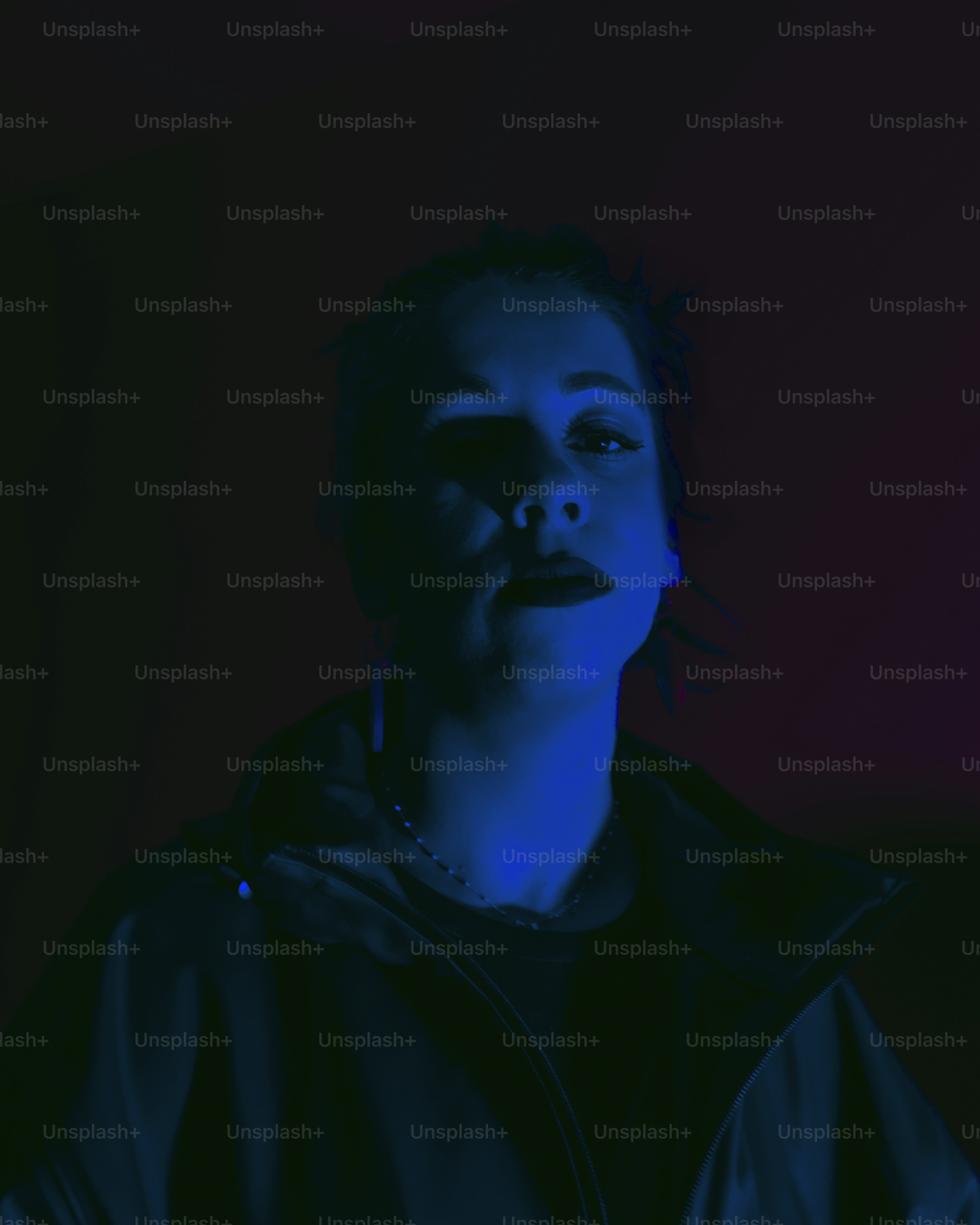 Frau starrt mit dunklem Make-up, das von Blau beleuchtet wird.