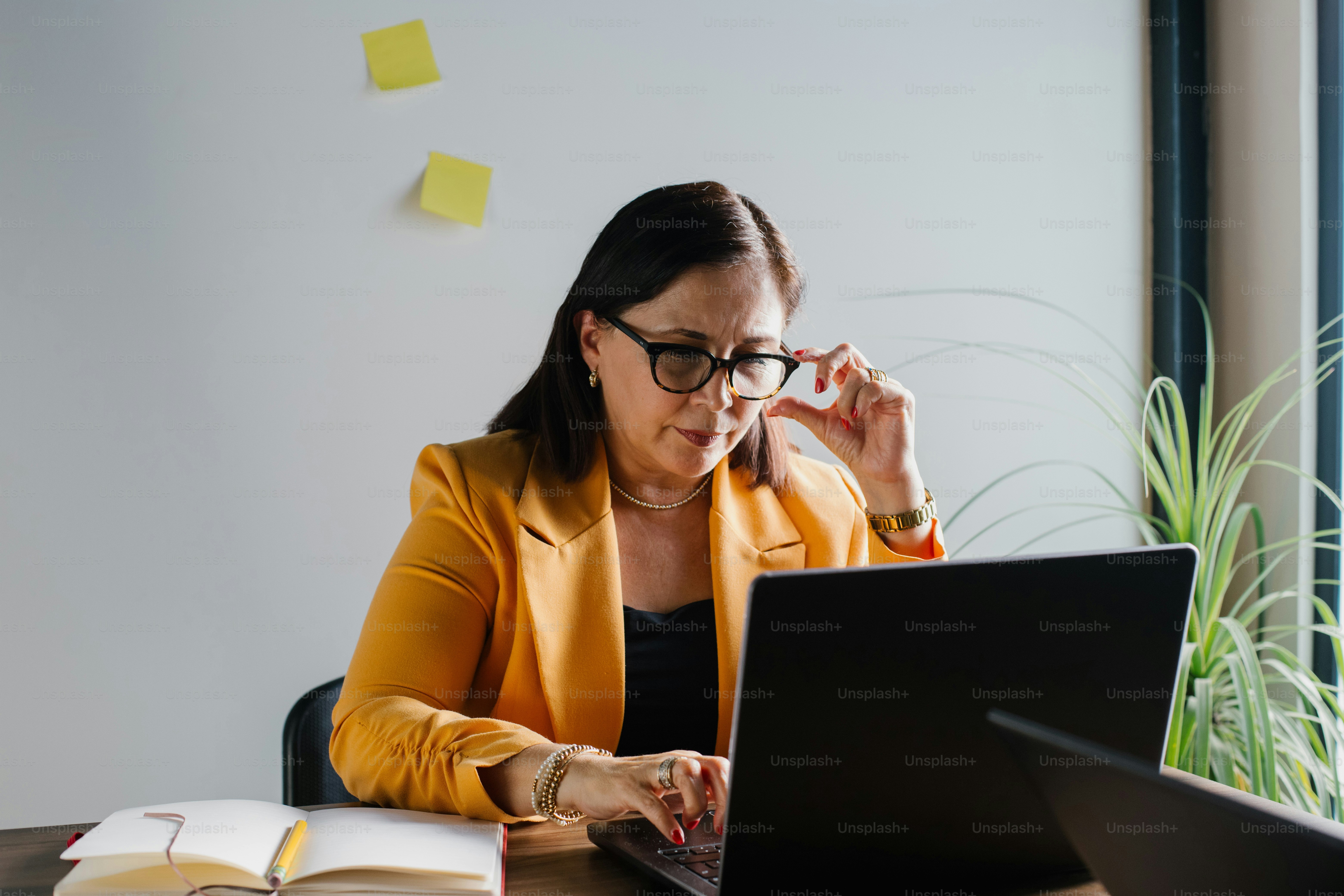 Woman with glasses works on her laptop.