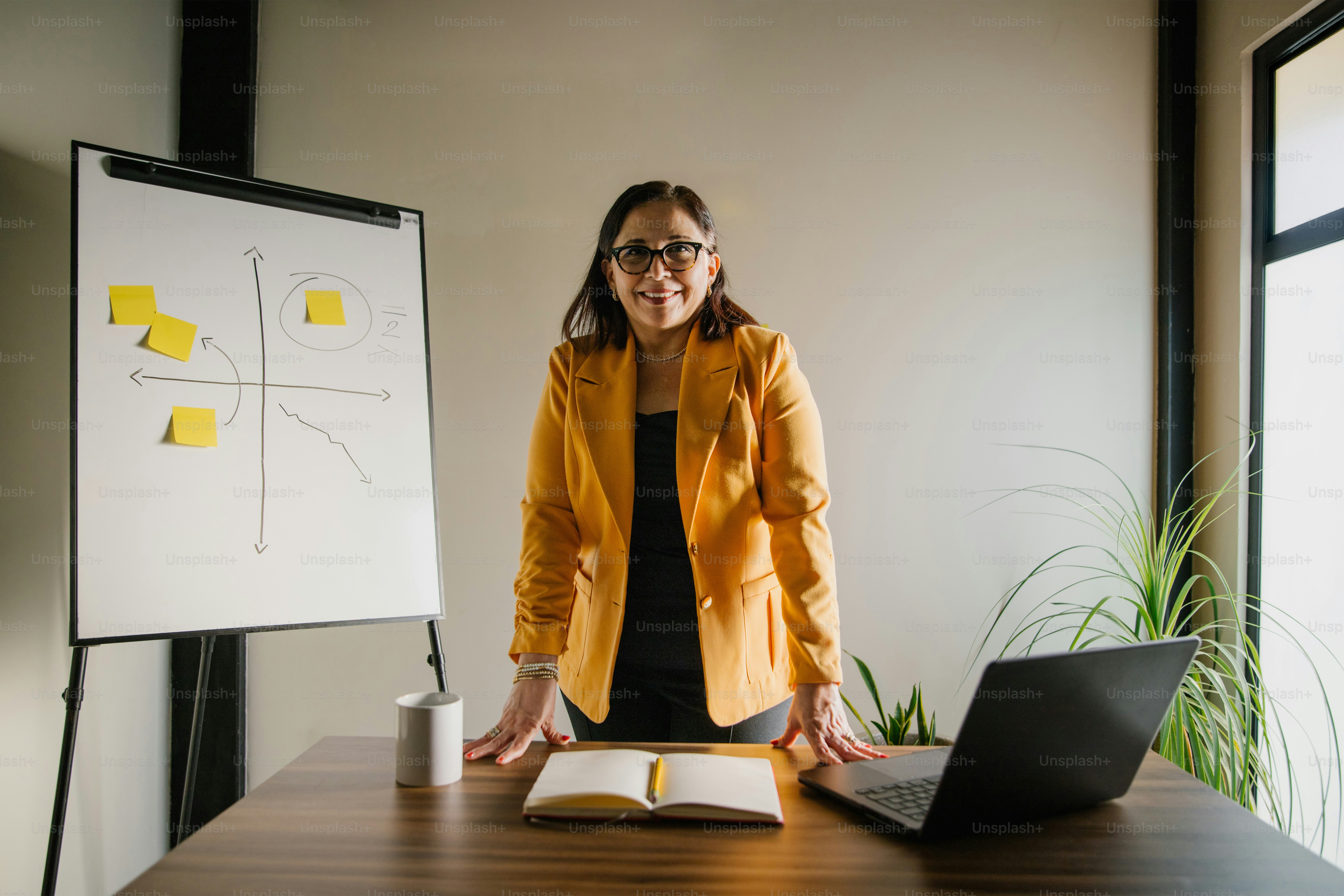 A woman stands near a whiteboard and computer.