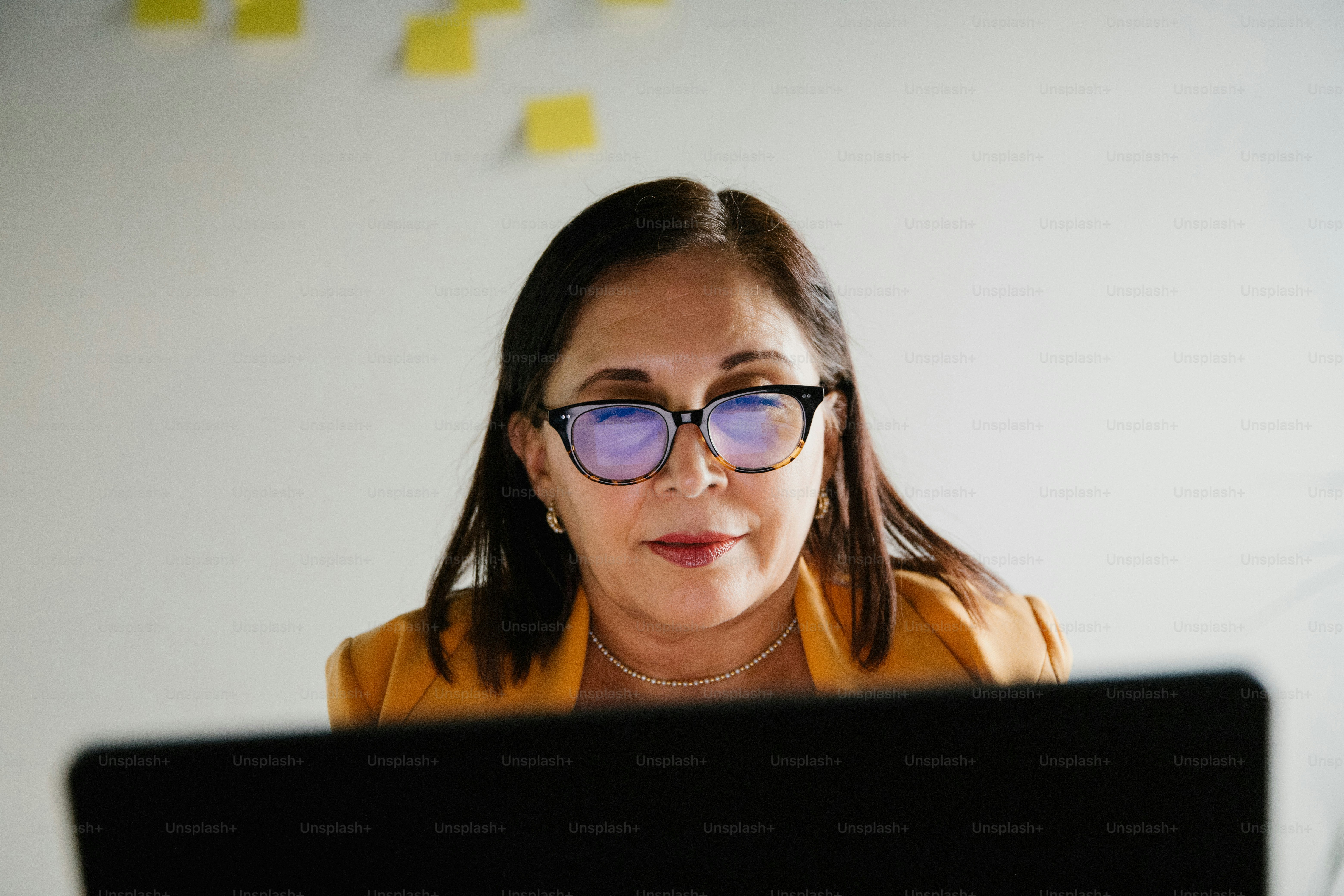 Woman with glasses looks intently at her computer.